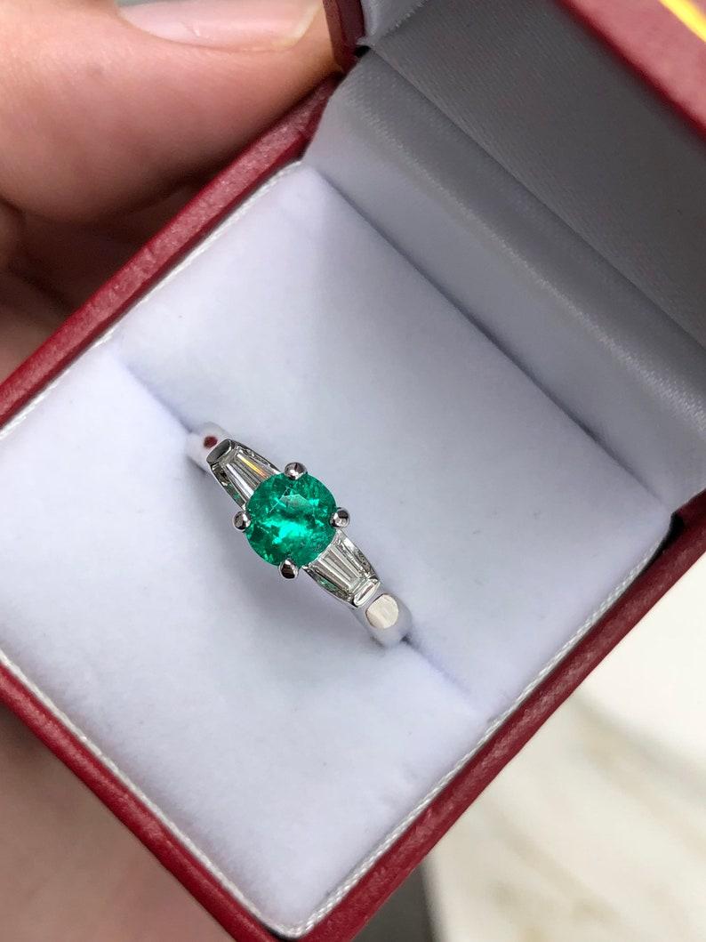 A classic Colombian emerald and diamond engagement, statement, or right-hand ring. Dexterously crafted in gleaming 14K white gold this ring features a 1.0-carat, fine quality natural round Colombian emerald from the famous Muzo mines. Set in a