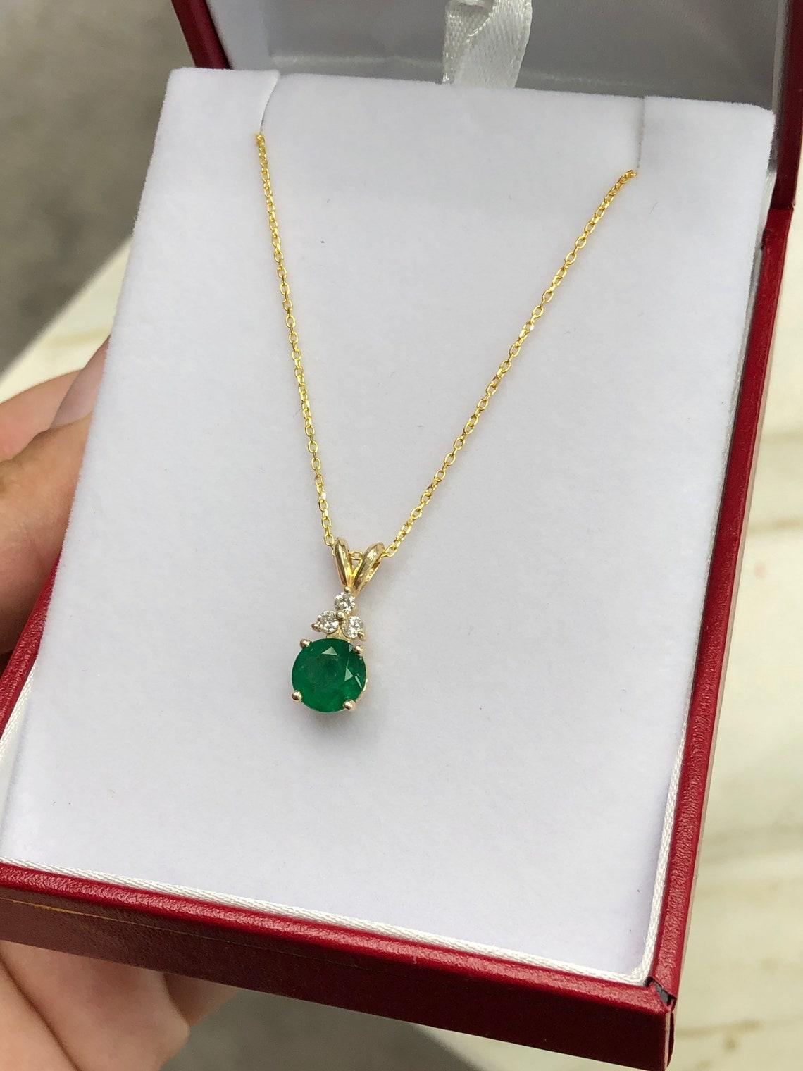 Qui è presentata una splendida collana di smeraldi naturali rotondi e diamanti in oro giallo 14K. In mostra c'è uno smeraldo di colore verde medio con un'ottima trasparenza, accentuato da una semplice montatura a quattro punte che permette allo