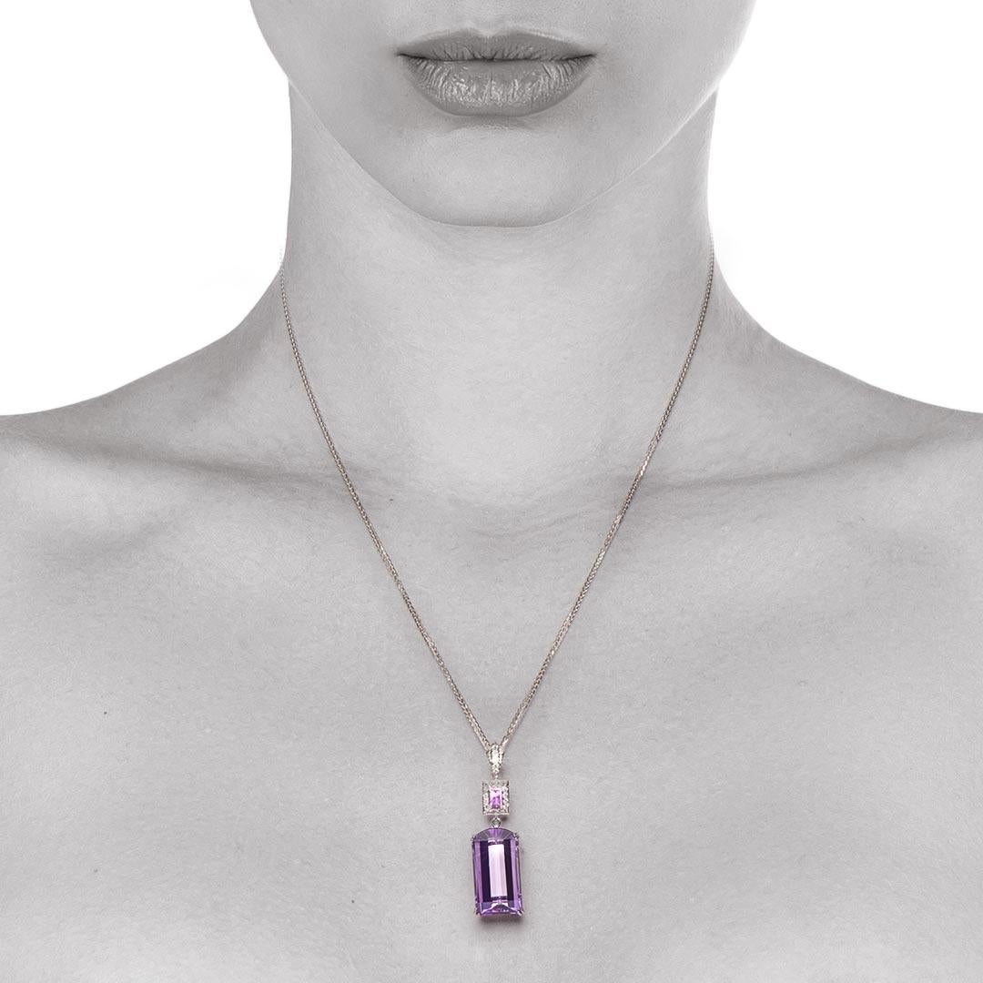A stunning pendant featuring a fancy shaped Amethyst weighing 13.60 carats. Its rich colour is beautifully contrasted by the vivid pink of a baguette shaped Pink Sapphire (weight of 0.71 carat) surrounded by fine grain set round brilliant diamonds