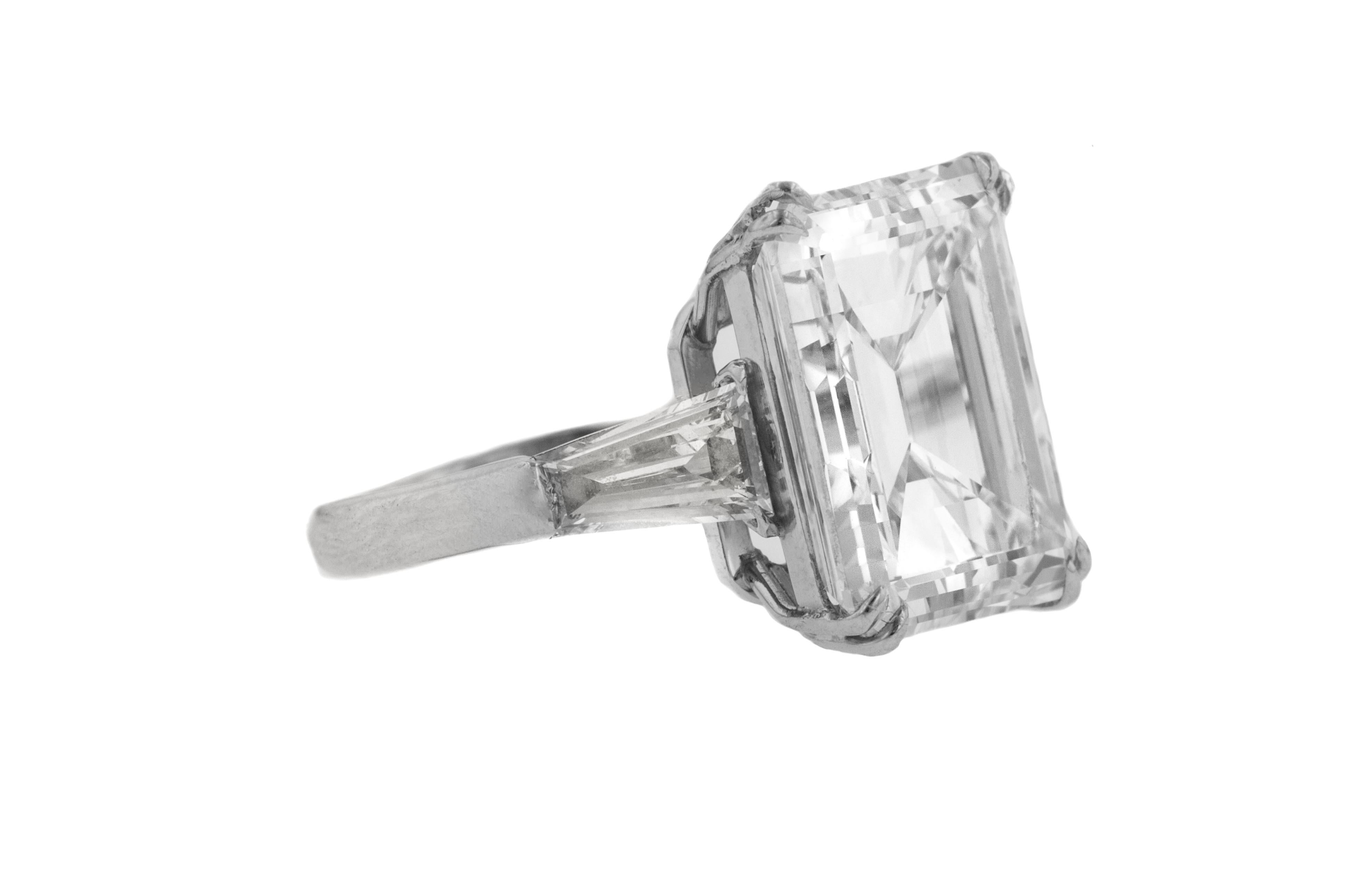 Platinum Diamond ring, features 13.61 Carats Emerald Cut J Color VVS2 certified by GIA and set with 1.50 Carats of trapezoids. 
