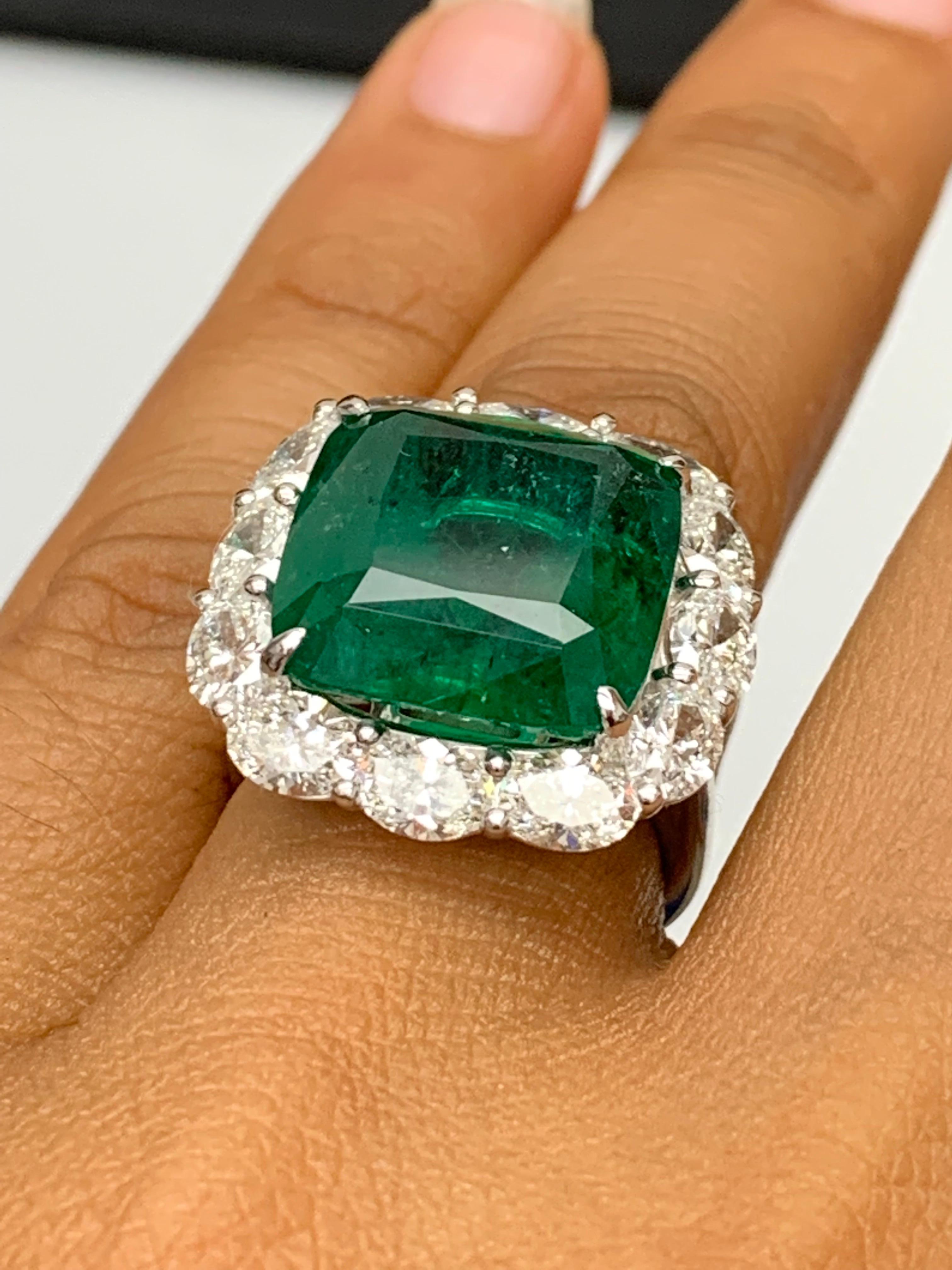 Une bague de fiançailles étonnante et bien fabriquée, mettant en valeur une émeraude vert vif de 13,65 carats, taillée en coussin. Le diamant central est flanqué de 12 diamants de taille ovale parfaitement assortis, d'un poids total de 5,51 carats,