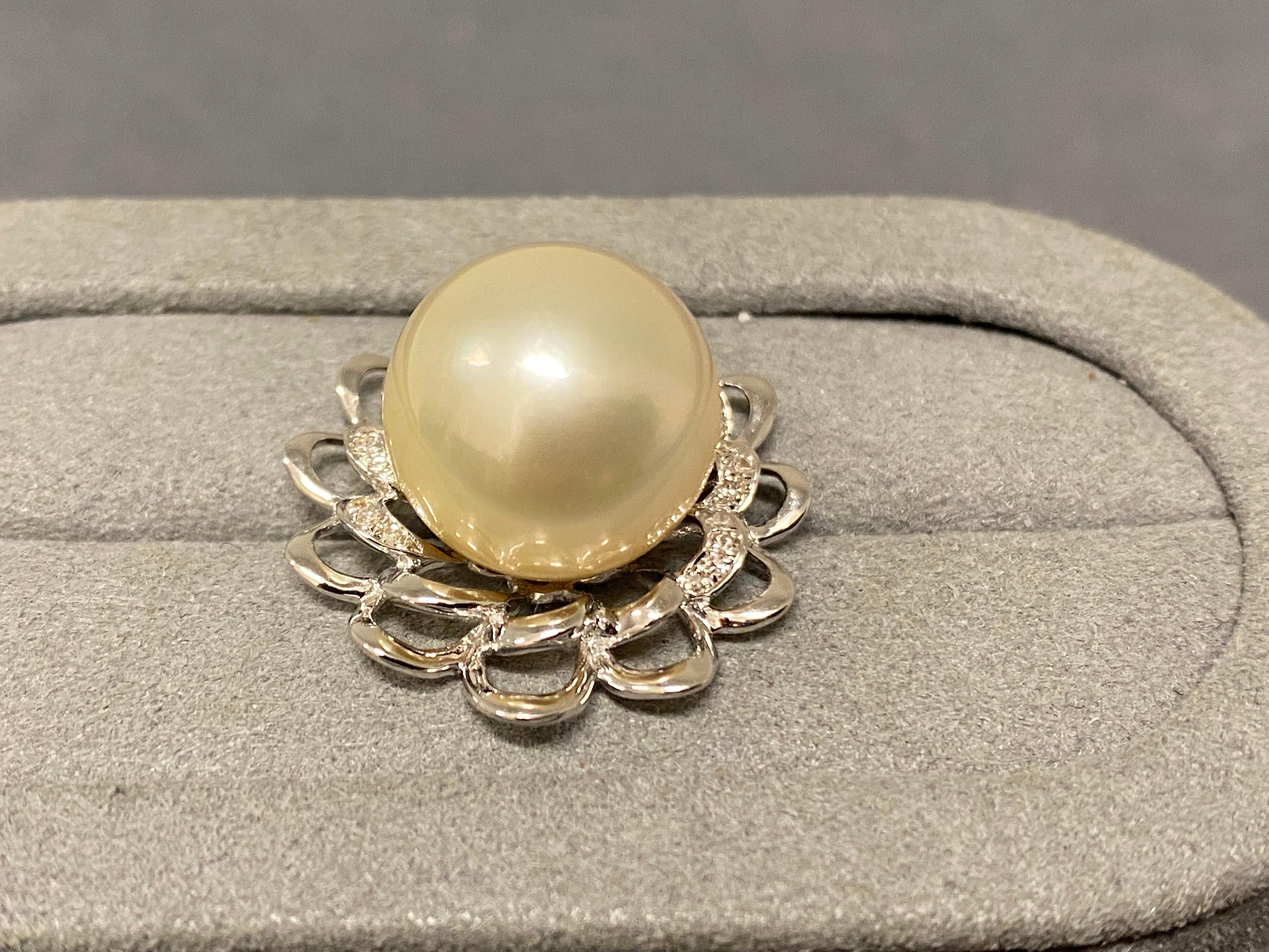 A 13.7 mm south sea pearl and diamond pendant in 18k white gold. The pearl is set in the middle of a daisy-like flower motif and some of the petals are set with micro diamonds. The south sea pearl is light champagne in colour with green overtone.