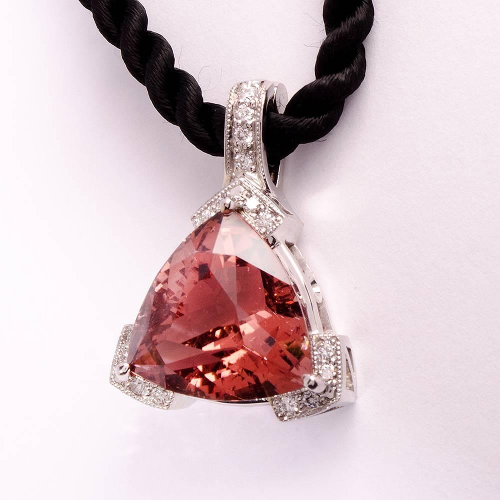 This classic, beautiful 14K white gold enhancer may be clipped on and off chains, pearls or beads. It features a beautifully cut trillion shaped pink tourmaline weighing 13.73 carats, measuring 16mmx 16mm. The center stone is surrounded by fine