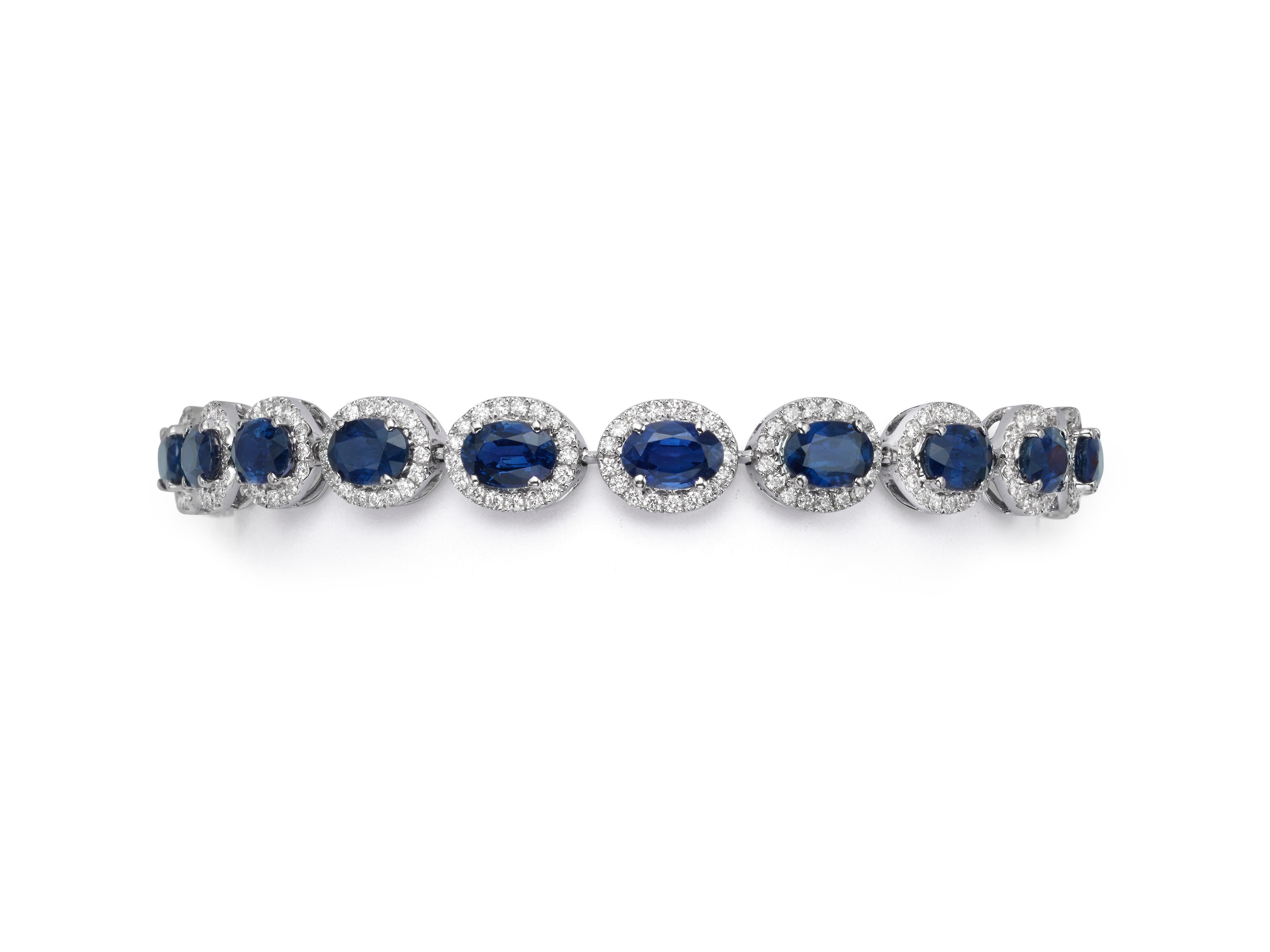 A sapphire and diamond cluster bracelet handcrafted from 18K white gold.  An oval blue sapphire sits in the center of each link and is encircled by a glittering halo of white diamonds.  The vibrant blue sapphires have a total weight of 11.90 carats