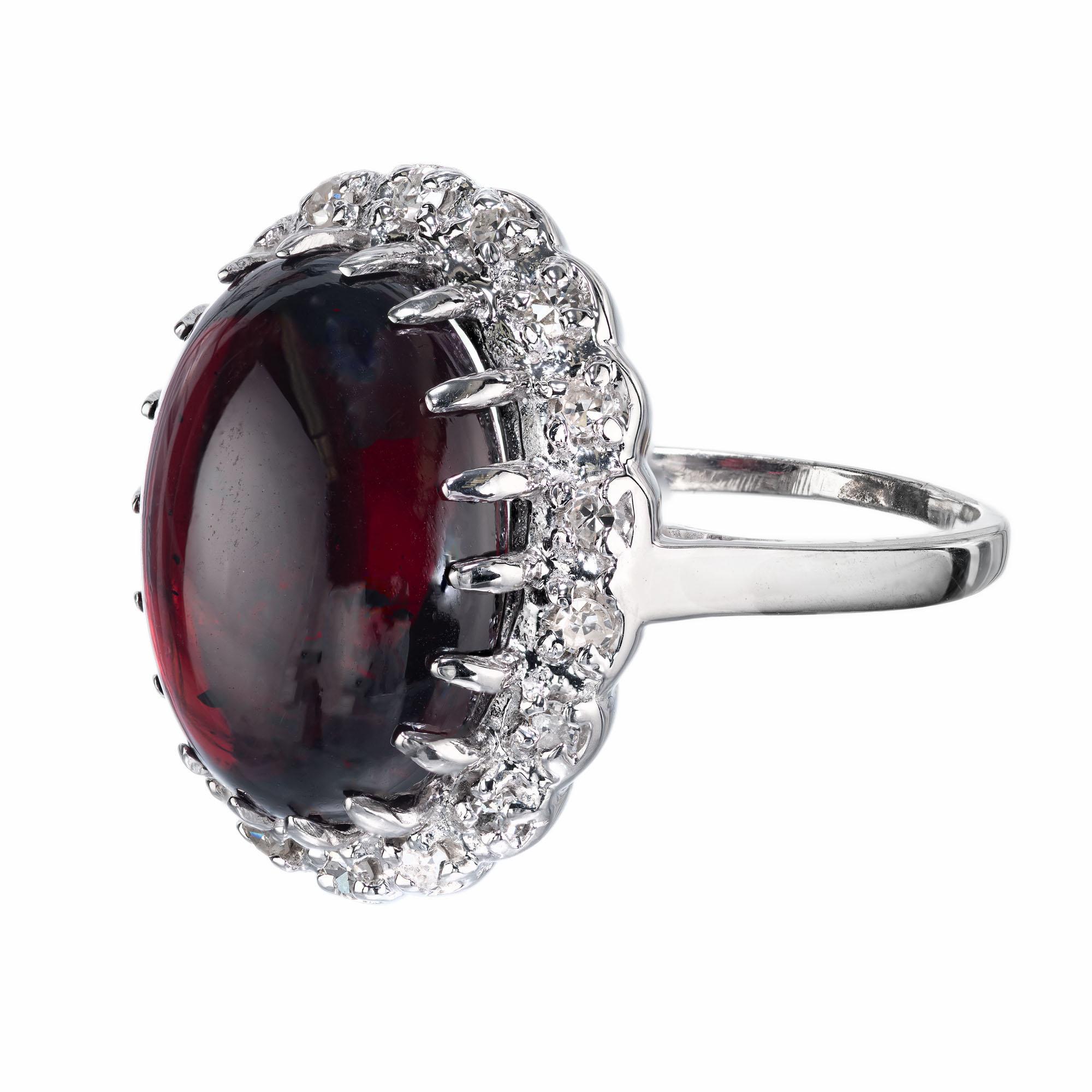 Cabochon garnet of translucent reddish-brown color surrounded by a bright white diamond halo in a 14k white gold setting.  Circa 1940-1950

1 oval reddish-brown garnet with natural inclusions, approx. 13.75cts
18 round single cut diamonds, H VS-SI