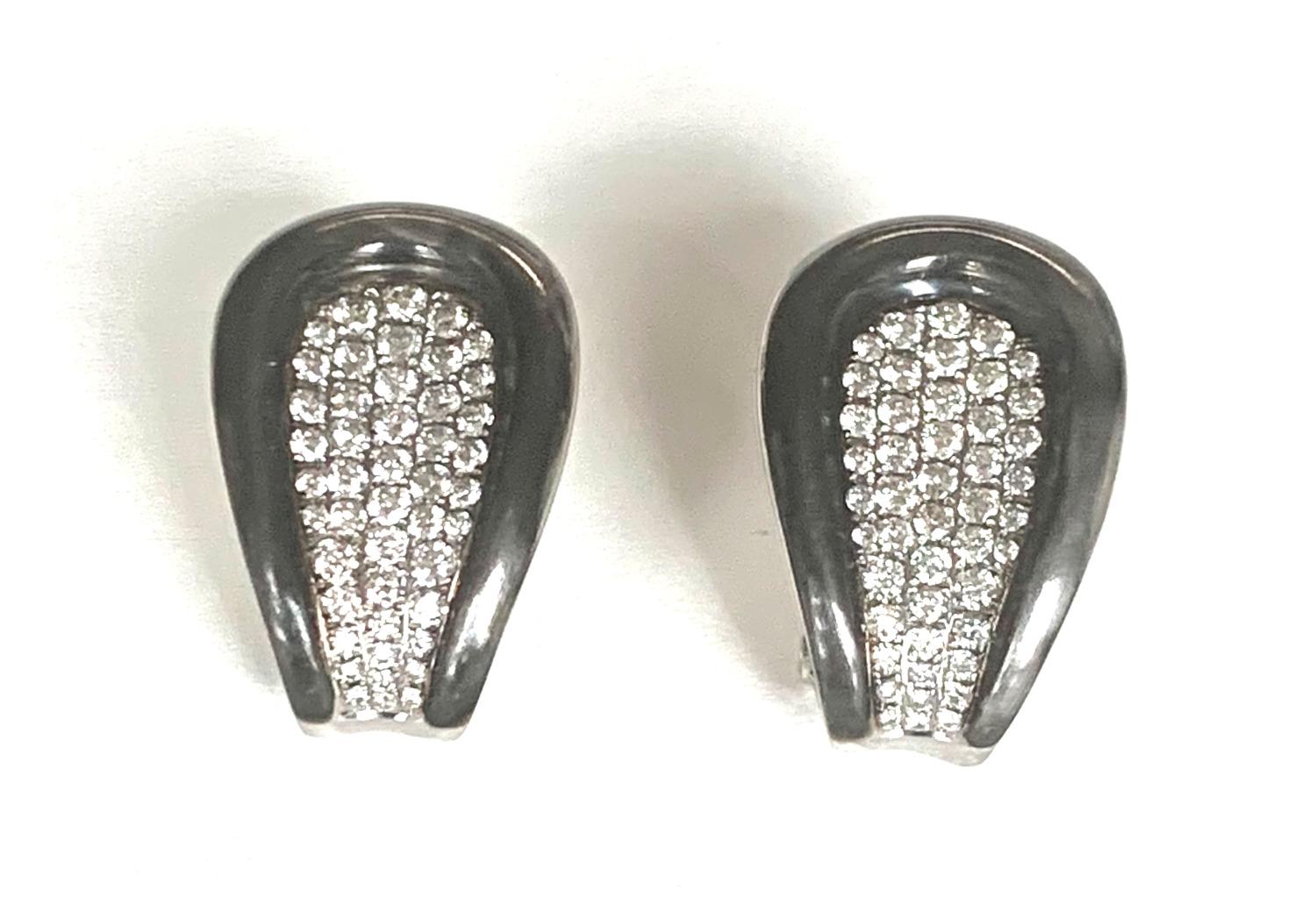 These 18k white gold and diamond-encrusted earrings are a study in contrasts, made with an unusual brushed gunmetal finish border that complements the elegantly pave-set sparkly diamonds. These striking earrings were made in Italy and have a chic,