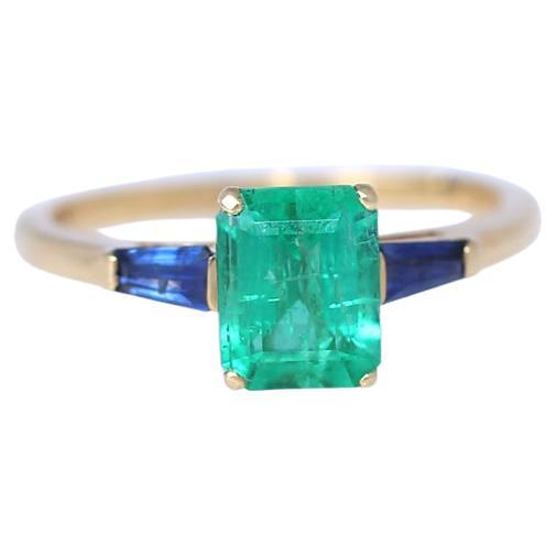 1.38 Ct Emerald Sapphires 18K Yellow Gold Ring.
Modern ring yet has a distinctive classic design. 18K Yellow Gold cast holding a 1.36 Carat Emerald center emerald-cut (rectangle) stone with two Sapphire on sides. The color combination of gold blue