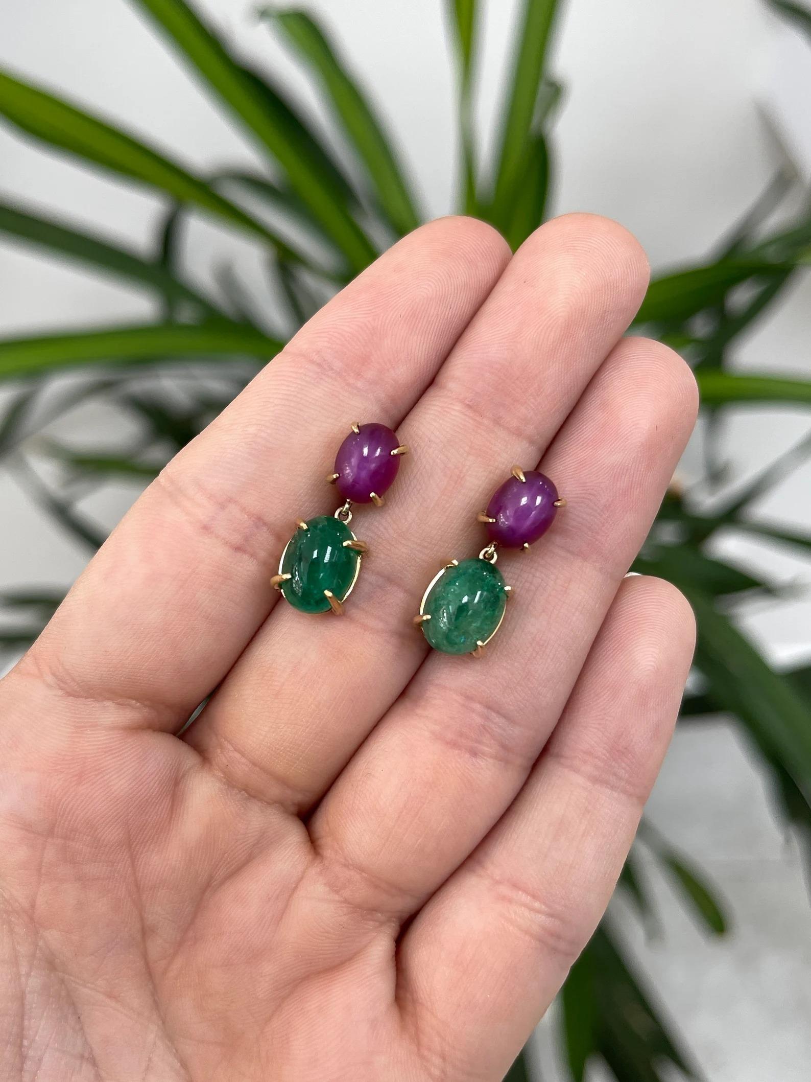 A spectacular, and one-of-a-kind pair of emerald and ruby cabochon dangle earrings. As the true statement piece it is, two ravishing 6-ray star rubies captivate all the attention with the unusual illusion of a dancing star within each one as it