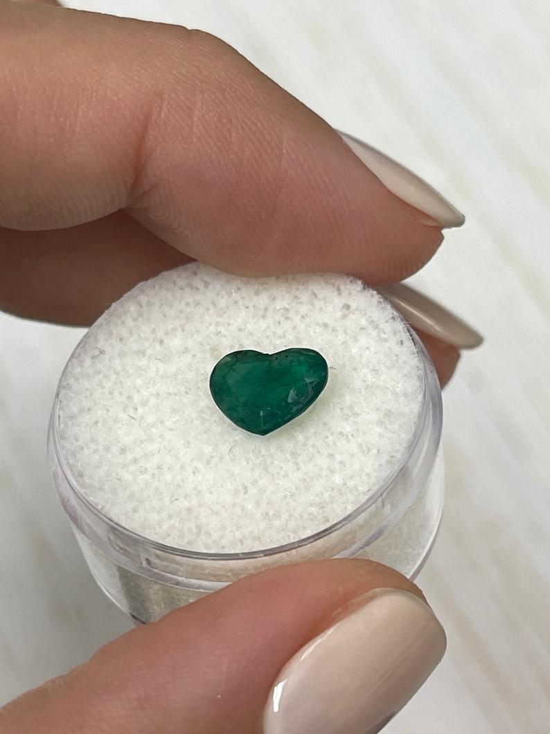 Stone: Emerald
Weight: 1.39-carats
Shape: Heart Cut
Clarity: Translucent
Luster: Good
Color: Dark Green
Measurements: 7.0mm x 9.09mm
Geographic Origin: Brazil
Treatment: Natural, Oiling

Comments: Due to their growth conditions in nature and