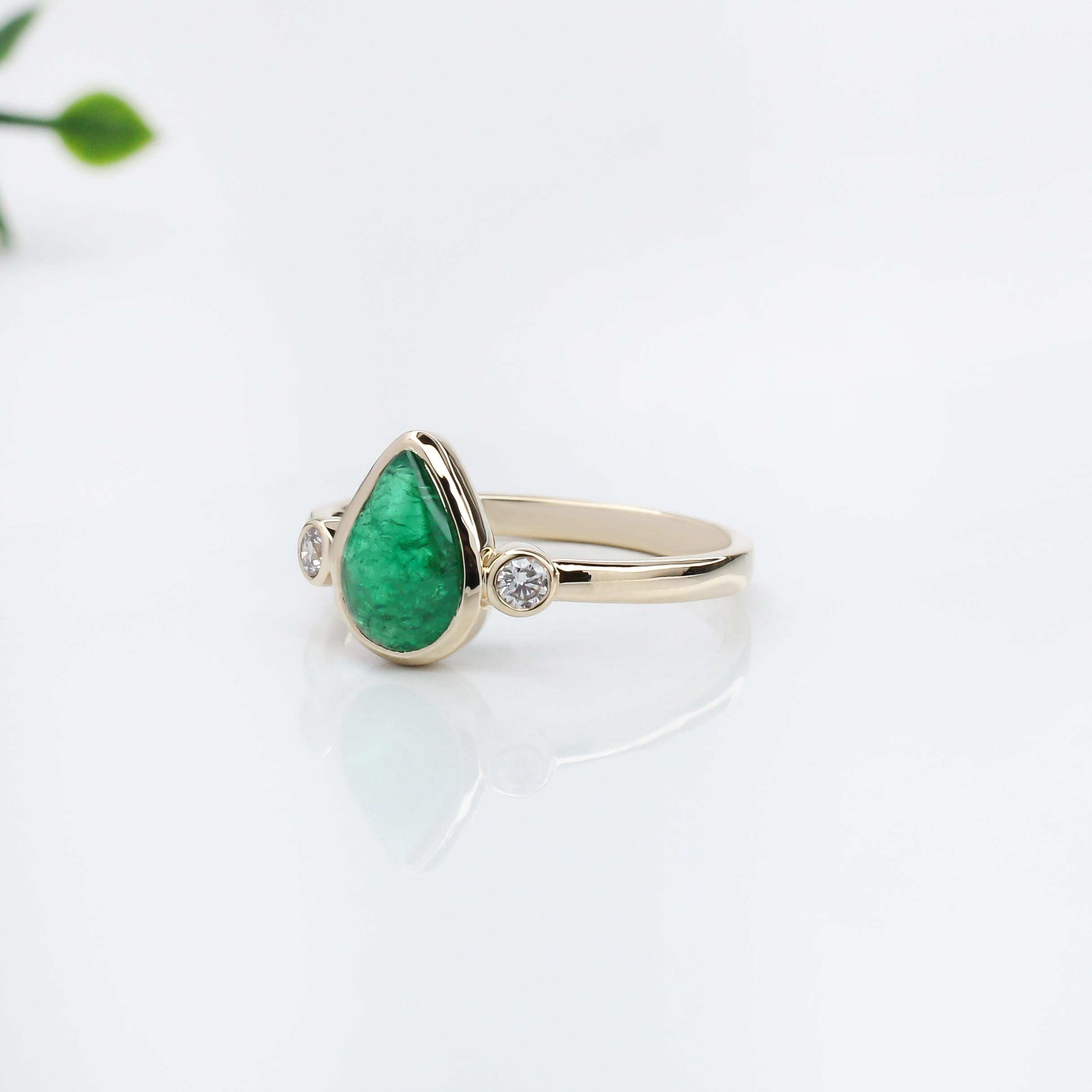 This ring showcases a striking 1.31 carat pear-shaped Emerald gemstone, flanked by two sparkling natural earth mined diamonds, all set in solid 14K gold. The emerald's rich green hue is beautifully complemented by the brilliance of the diamonds,
