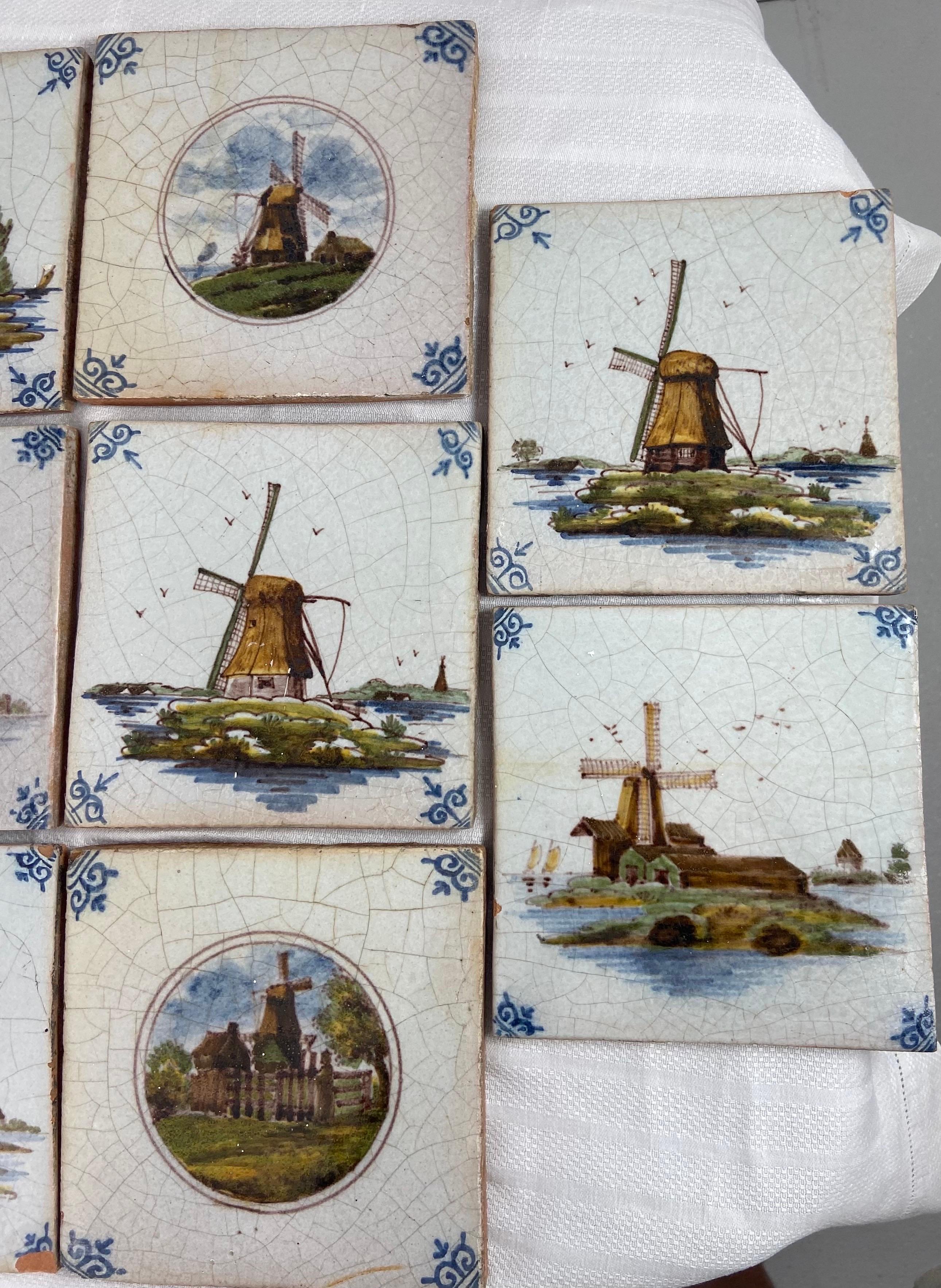 A set of 14 antique delft tiles poly-chromed. each tile depicts a unique windmill scene