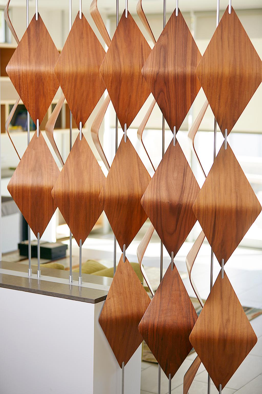 The walnut window shades are an exploration of three dimensional tessellations; giving a flat pattern form. The shades hide and reveal what is behind through a simple rotation of each bar. When situated in front of a window they register different