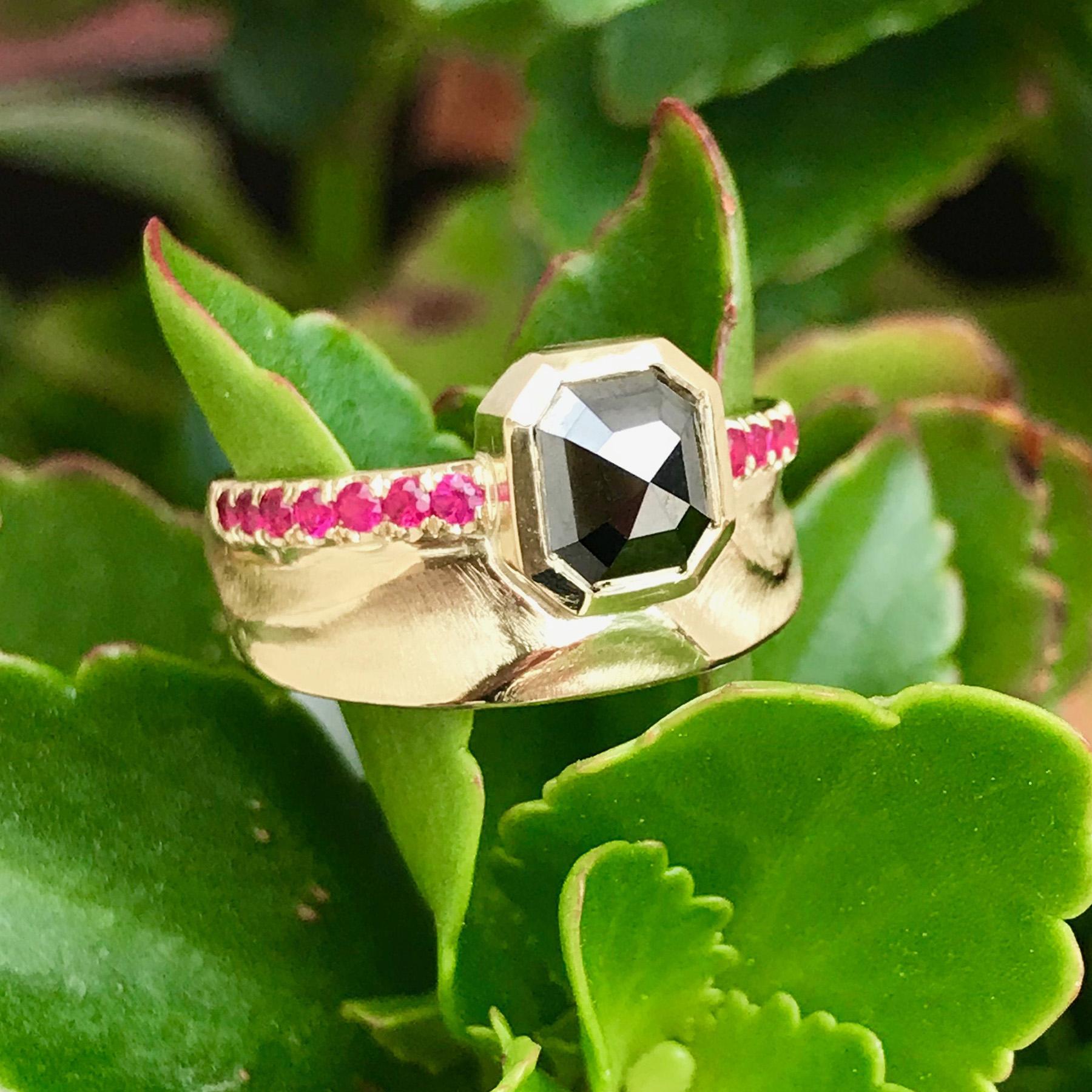 K.Mita's contemporary Noire Scarletta Ring, which is handmade by the artist from 14 Karat Yellow Gold, features a 1.4 Carat Black Diamond and 0.28 Carat Pink Sapphires around the edge. The width of the band is 8.5mm, but at its widest in front of