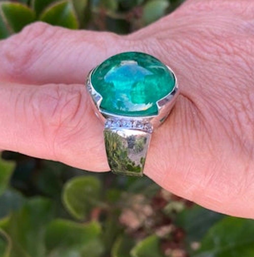 Gorgeous Emerald Cabochon Ring is set in a contemporary style setting with accenting diamonds, channel set on its side. Gorgeous color. Bold half bezel setting for Emerald with wide 10.50 mm shank graduating to 5.72 mm backing of the ring.