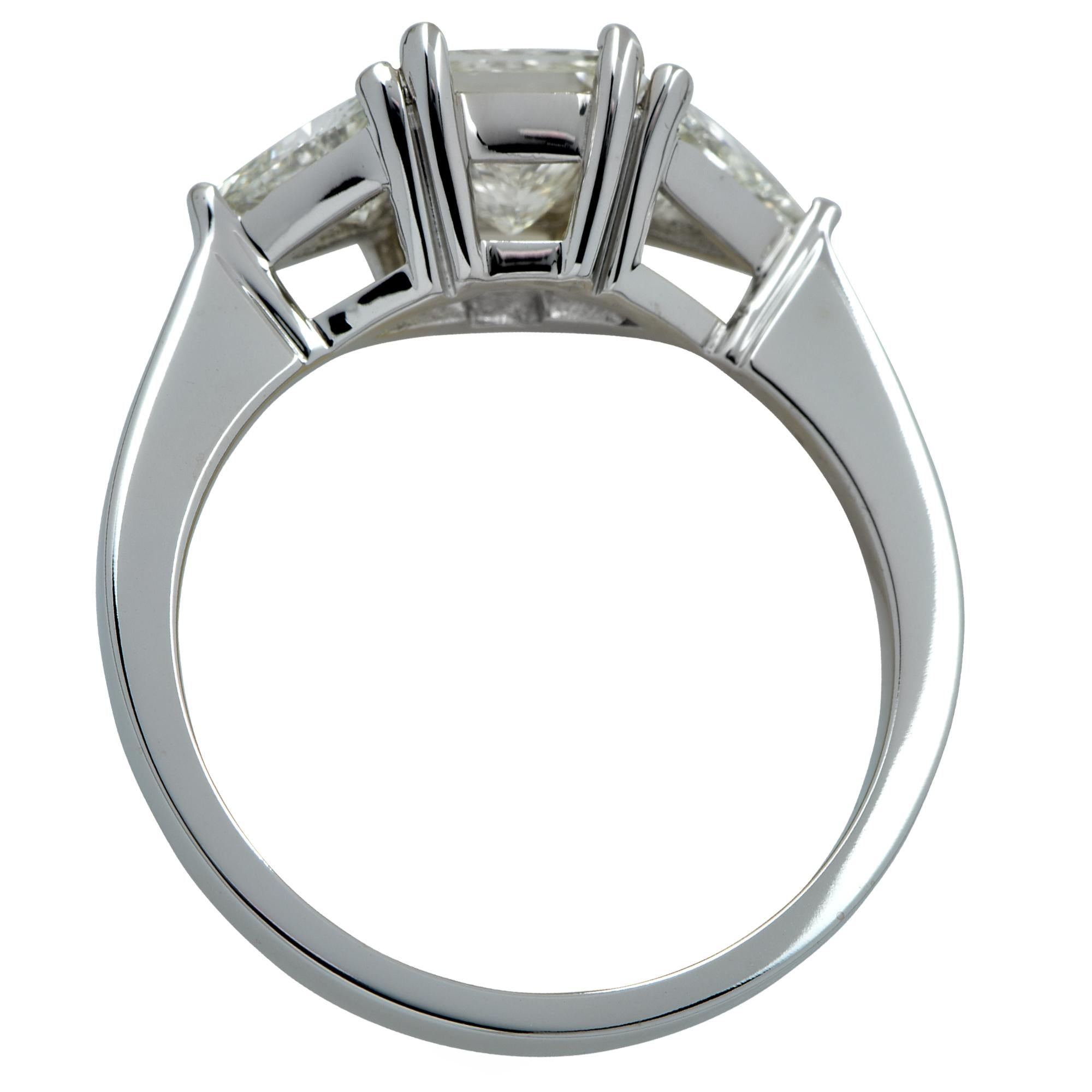 Stunning 14k white gold three stone ring showcasing a princess cut diamond weighing approximately .90cts K color SI clarity accented by 2 trillion cut diamonds weighing .50cts total, J color VS clarity. The band of this size 6 ring measures 1.42mm