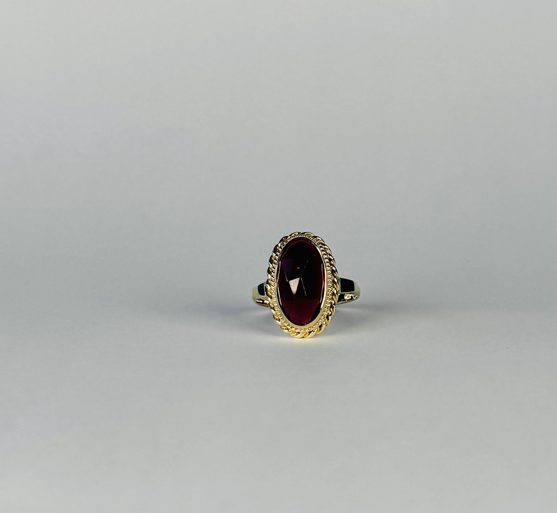 Pre-loved yellow gold ring which with a faceted garnet of approx. 4.66 carat. This stone is set in an open case setting. The ring features a twisted band and has beautiful  decorative details. The details of this pre-loved jewel is both charming as