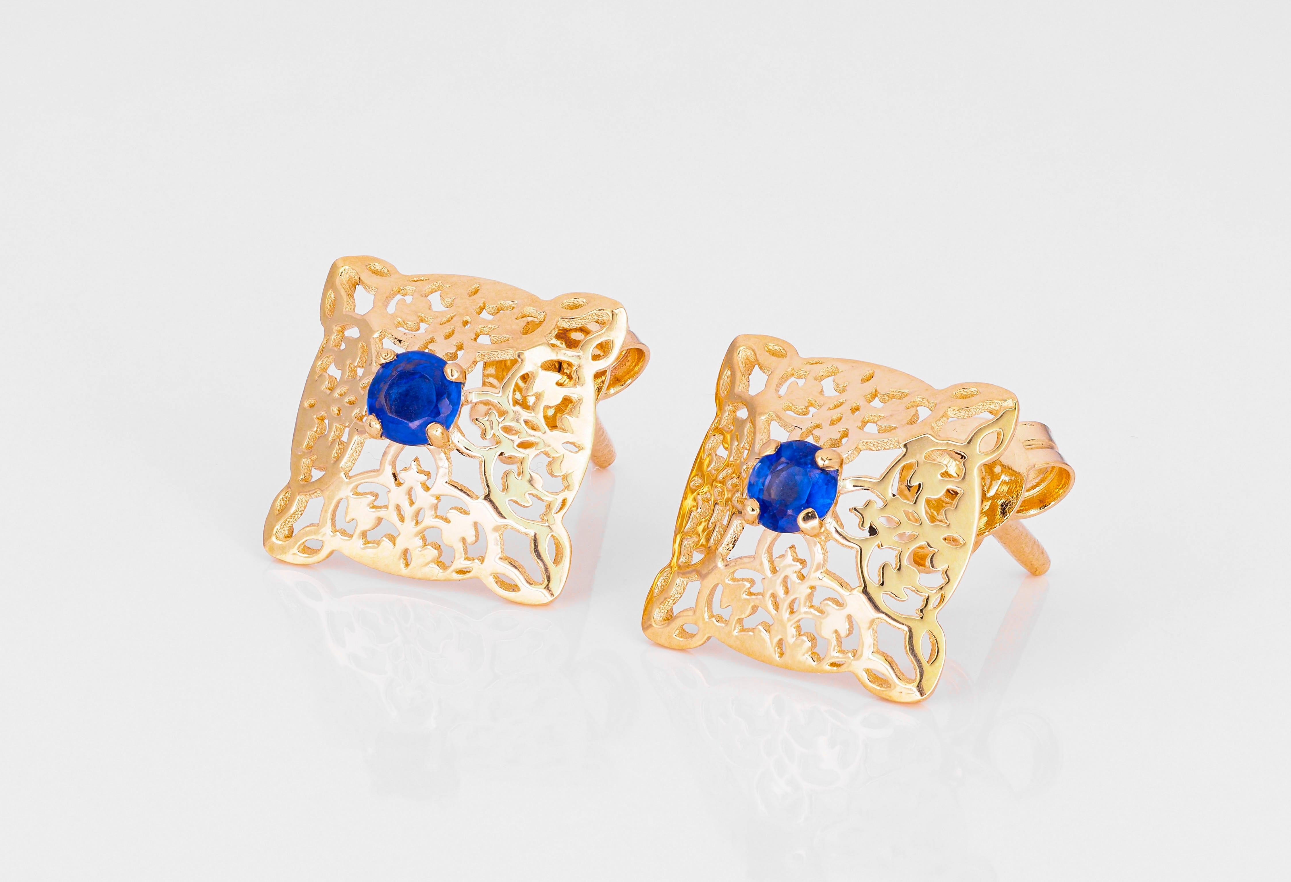 14 kt solid gold earrings with oriental pattern set with central natural sapphires. September birthstone.
Weight: 2.0 g.
Size: 16 x 11.5 mm.

Central stones: Natural sapphires 
Weight: approx 0.23 ct total (0.11 ct + 0.12 ct = 0.23 ct), 2 pieces,