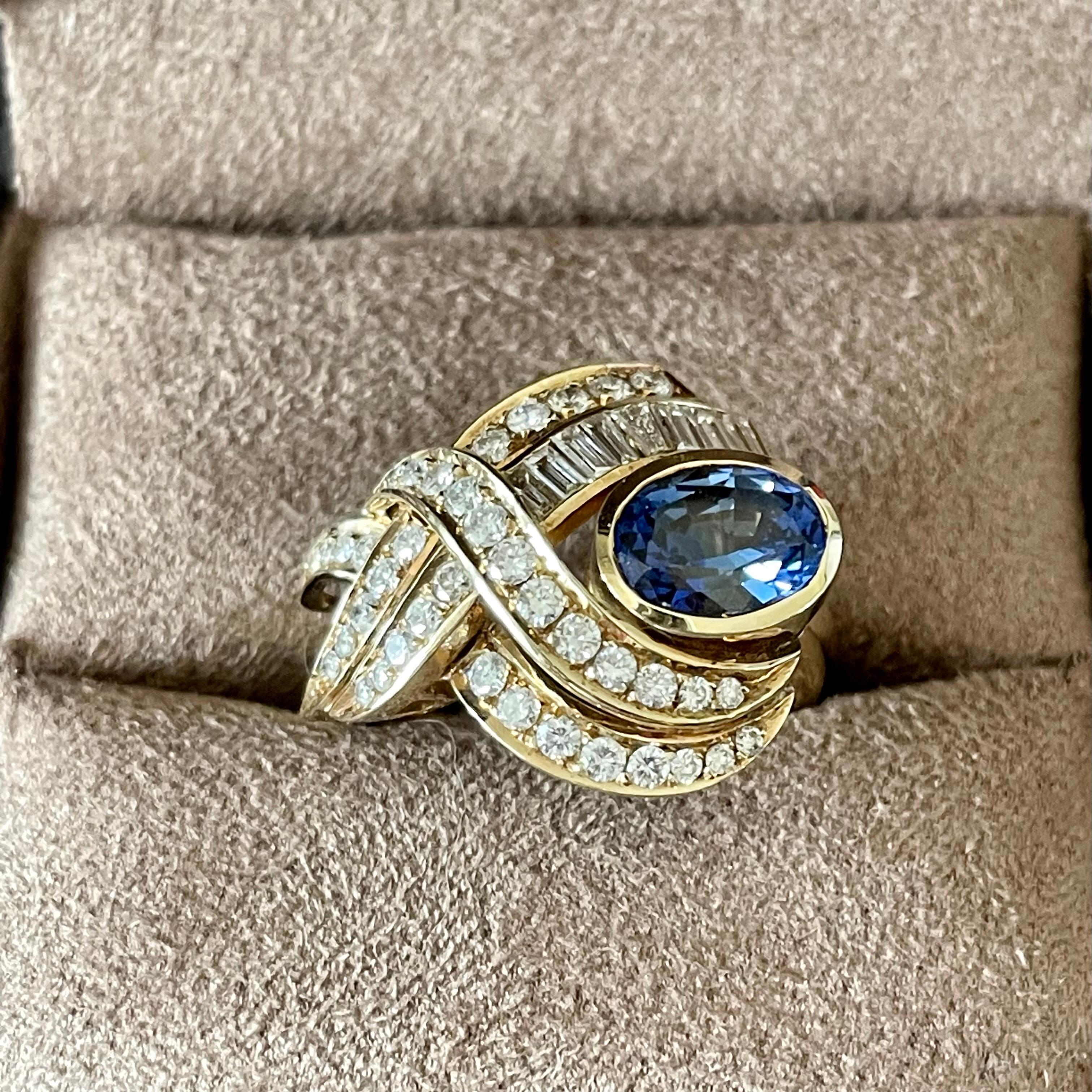 Fesselnder Cockatail-Ring aus 14 K Gelbgold mit einem schönen blauen ovalen Saphir von ca. 1,80 ct, umrahmt von Diamanten im Baguette- und Brillantschliff von ca. 2 ct. 
Der Ring hat derzeit die Größe 54 (US-Größe 7), kann aber leicht in der Größe