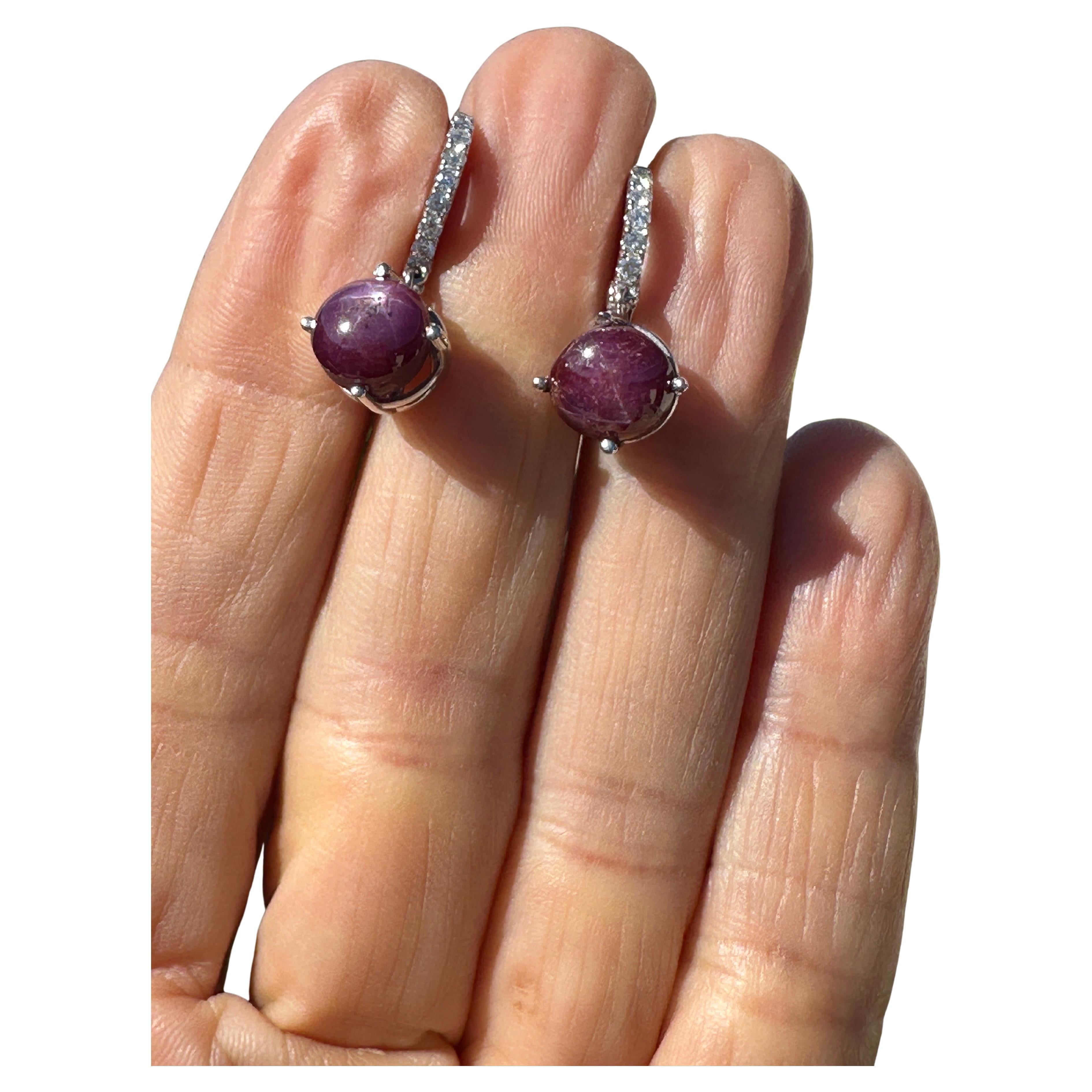 Realizzati con maestria in oro 14kt, questi orecchini a cerchio con cerniera penzolante presentano uno splendido rubino a stella da 5 carati e accenti di diamanti da 1/3 di carato. Eleganza, movimento e scintillio di questi orecchini. Realizzato