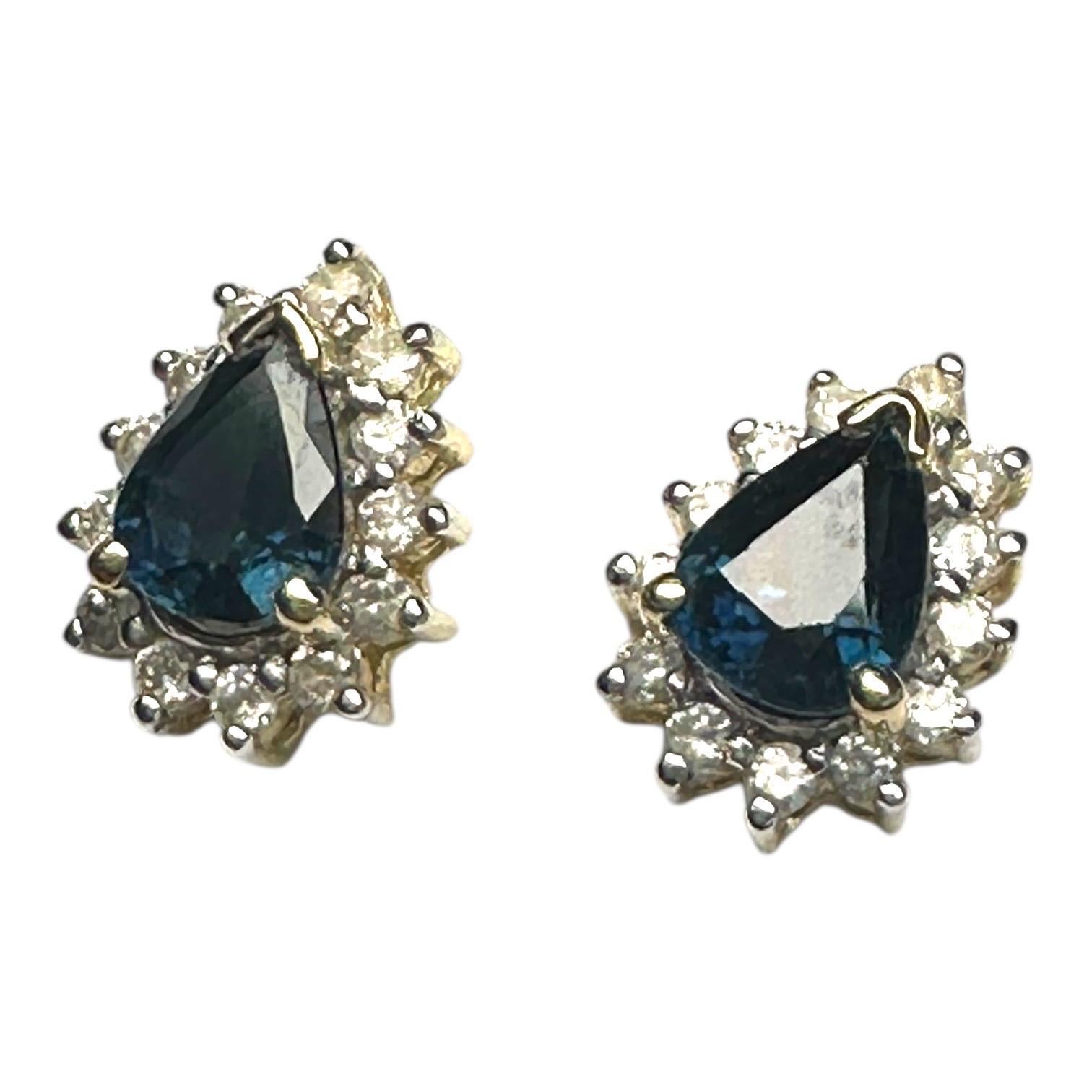 Ces boucles d'oreilles 14 carats présentent des saphirs naturels en forme de poire de 10 x 8 mm, chacun entouré d'un halo de diamants naturels. Ensemble, les saphirs et les diamants totalisent 0,85 carat, combinant un éclat brillant avec une couleur
