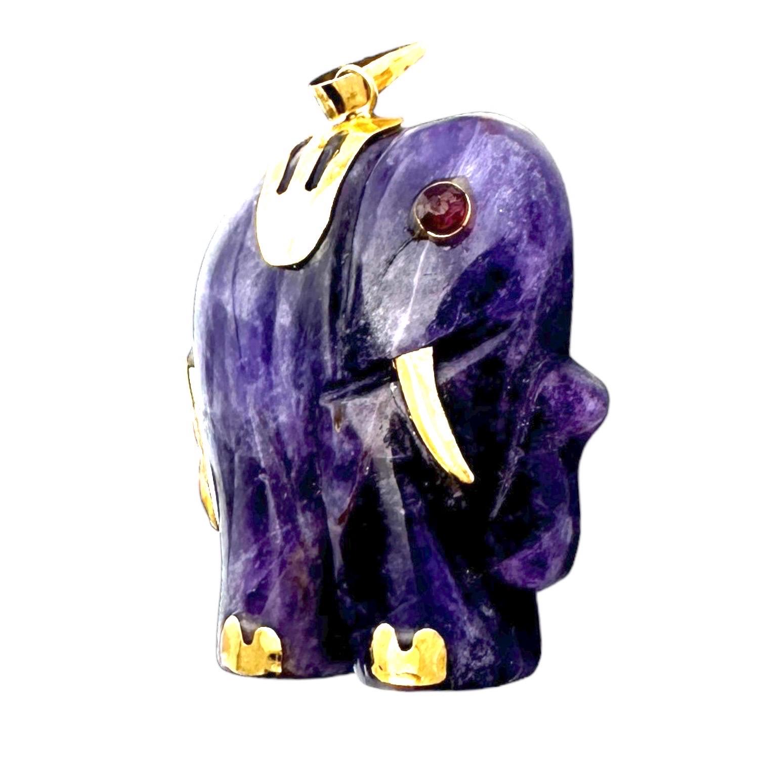 Realizzato con un'ametista africana di 14 carati, questo ciondolo a forma di elefante è caratterizzato da un design in oro con accenti di rubino. Con una gemma cabochon incastonata che misura 1 pollice di diametro, questo ciondolo è un'aggiunta