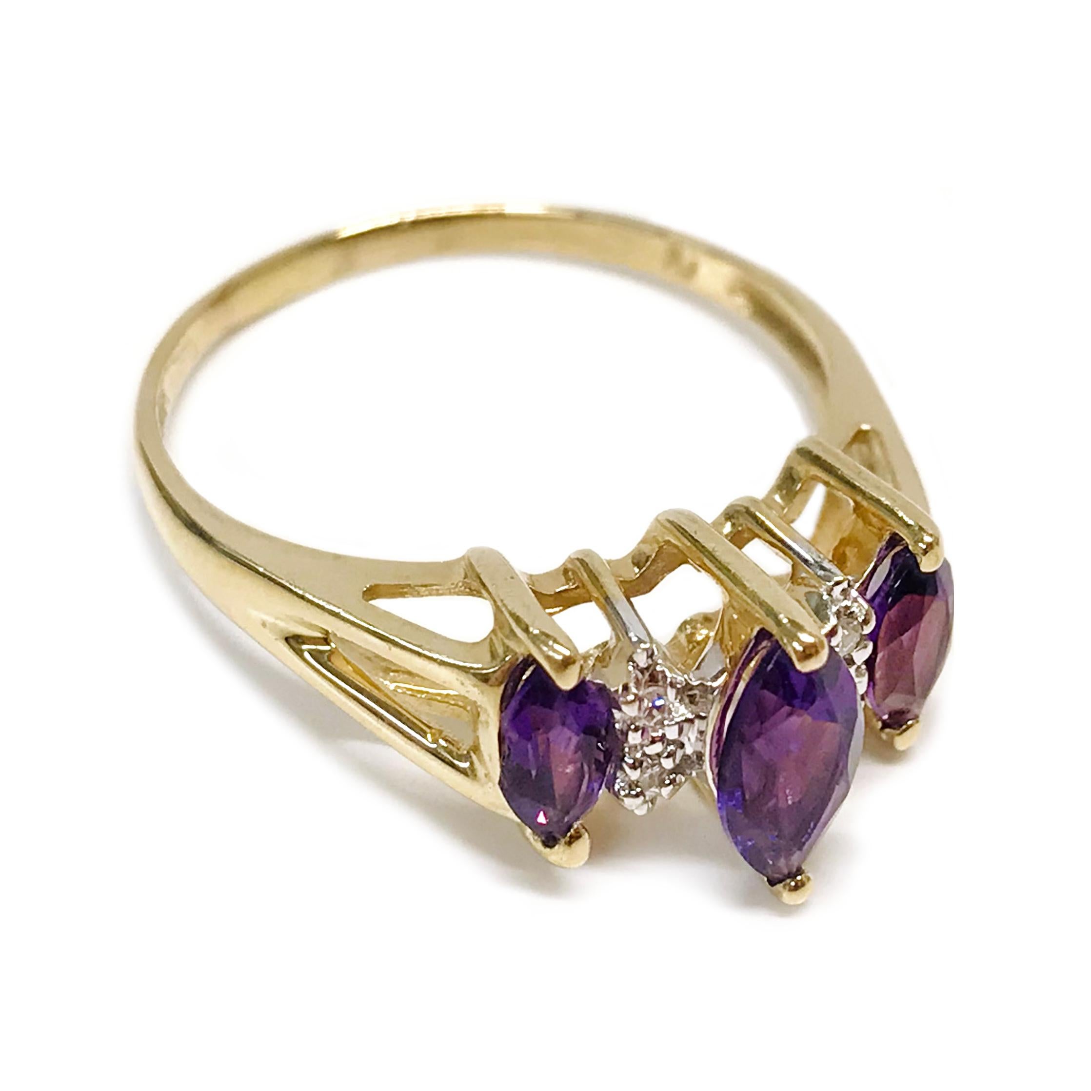 14 Karat Yellow Gold Amethyst Diamond Ring. The ring features three prong-set marquise Amethyst gemstones and four round diamonds. The split band ring is size 8. The center Amethyst measures 7mm x 3.5mm, the two smaller Amethysts measure 4mm x