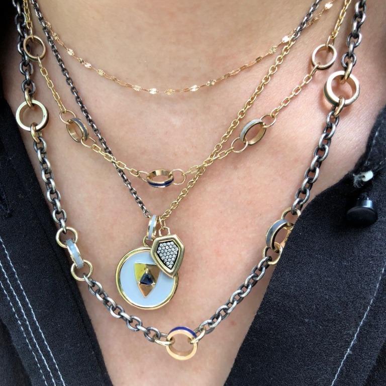 An oxidized chunky silver chain interspersed with larger gold round links.  Each of these gold links has a stripe of  varied colored enamel.  With bold color and mixed metals, this is a an updated version of a chain link necklace.   It is