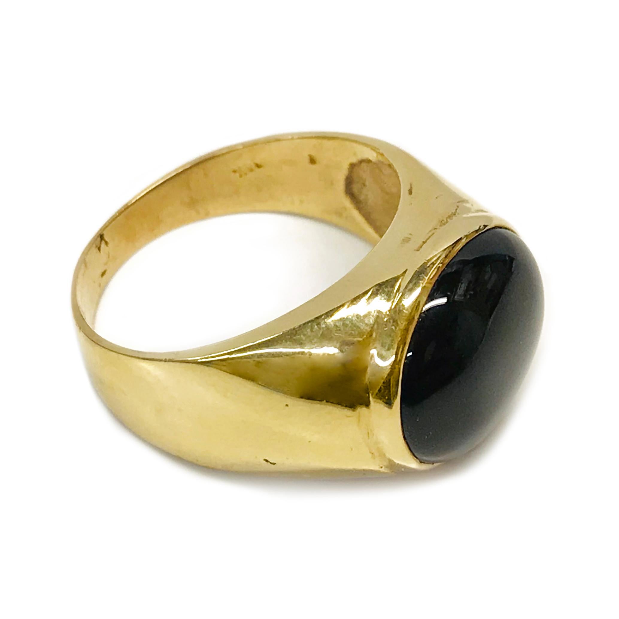 14 Karat Black Onyx Cabochon Ring. The ring features a bezel-set oval black onyx. The onyx stone measures 13mm x 11mm and the ring size is 8 3/4. The ring has a smooth shiny finish on the tapered band. Stamped on the inside of the band is 14K. The
