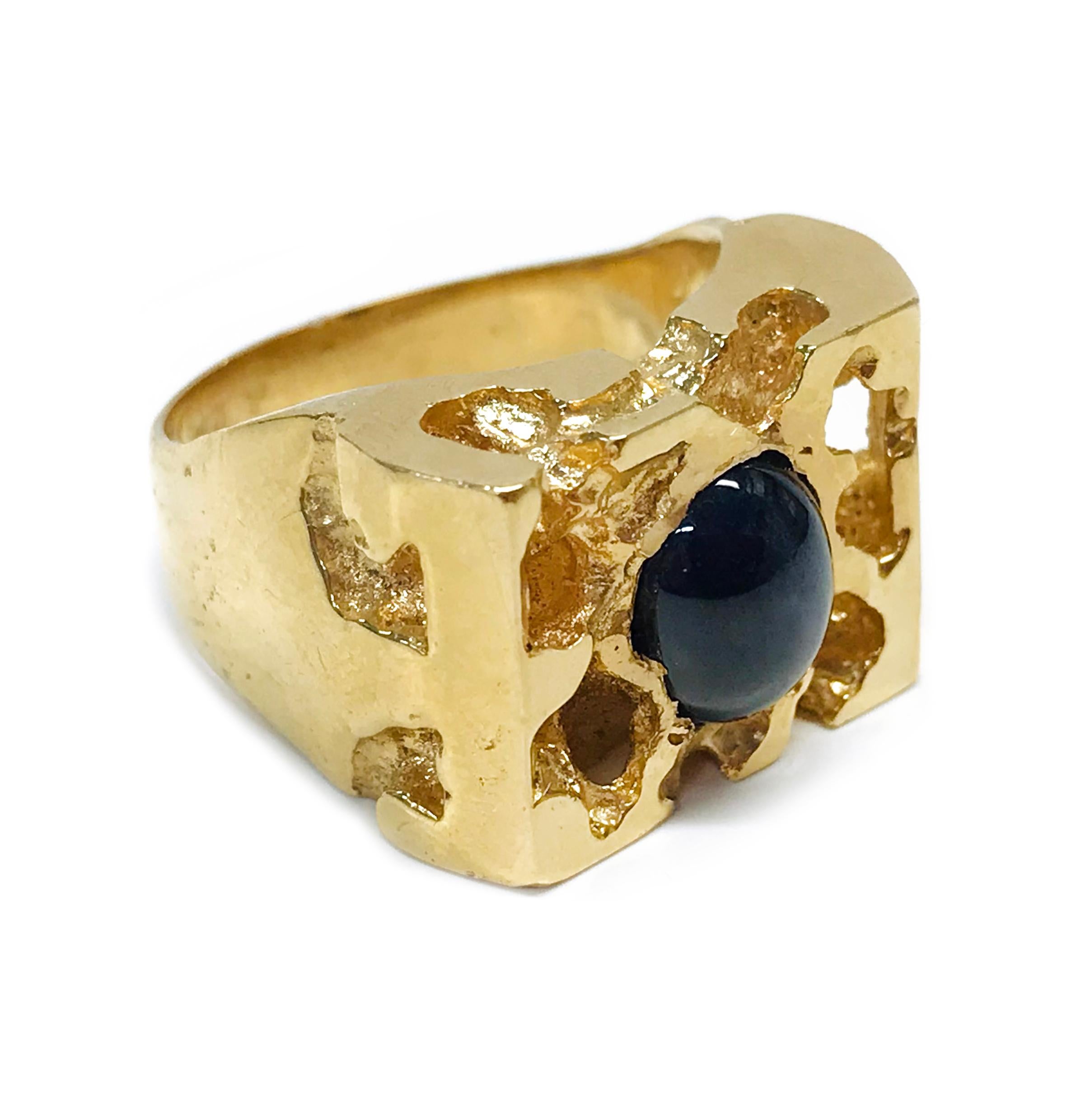 14 Karat Blue Sapphire Nugget Ring. The heavyweight ring features a bezel-set oval blue sapphire cabochon. The sapphire total carat weight is 2.98ct. The rectangular face has a nugget texture that is carried over to the side of the tapering band.