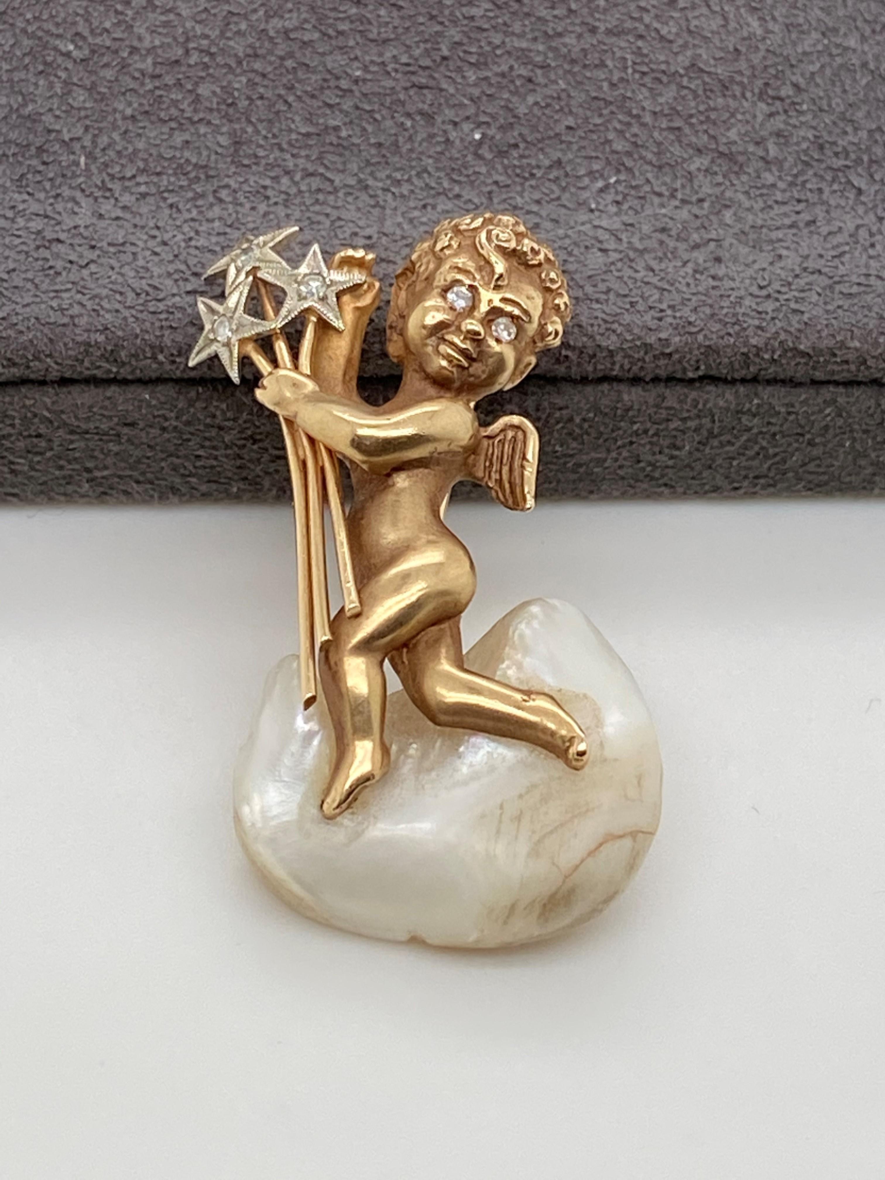 14kt yellow gold pin fashioned like a cherub holding a bouquet of stars and standing on a cloud made of mother of pearl. The diamonds weigh approximately .05 ct K-L color/ SI1-SI2 clarity. The pin dates to the 1950's and measures 1