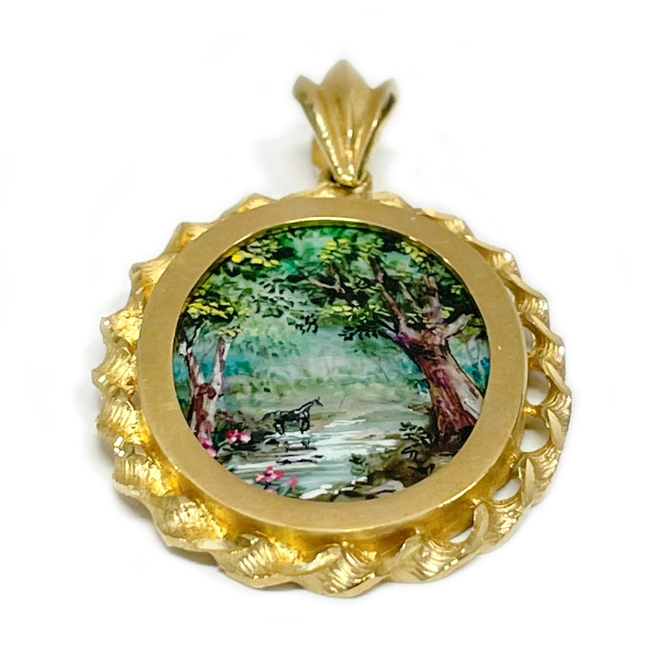 14 Karat Yellow Gold Creek with horse in the background Hand Painted on a Mother of Pearl Pendant. The miniature painting is set in a 14 karat gold twisted rope oval frame with diamond-cut details. The painting is signed by the master artist, CR