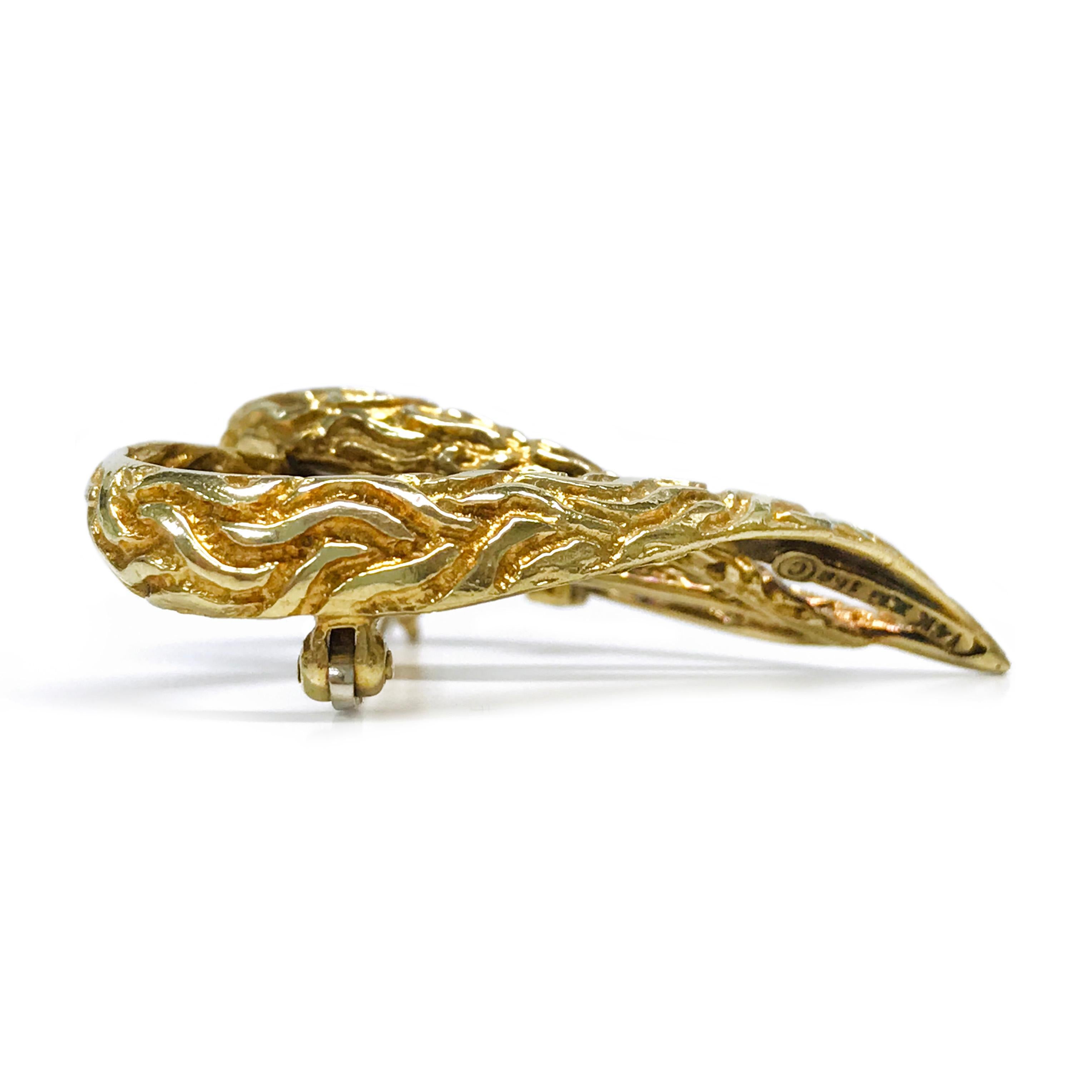 This elegant 14K gold diamond heart brooch features two gracefully interlocking loops forming a heart shape. A single round diamond, securely set in a four-prong setting, adorns the inner curve of one loop, adding a subtle yet brilliant sparkle. The