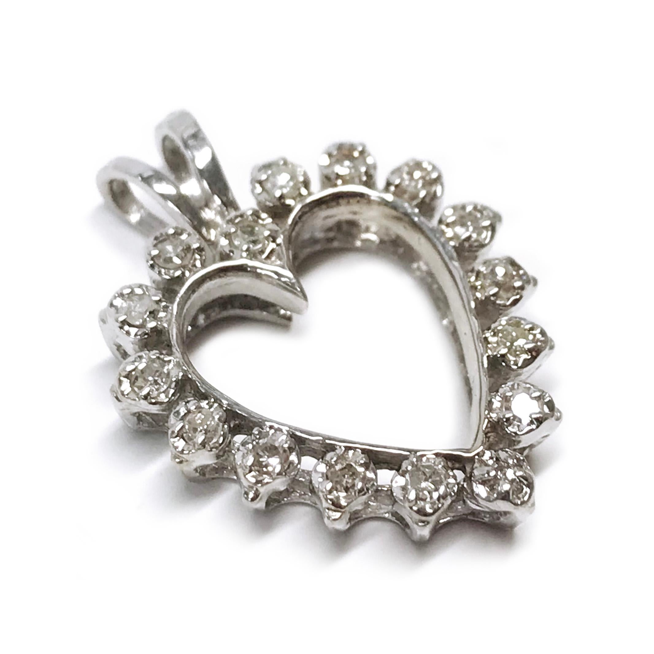 14 Karat White Gold Diamond Heart Pendant. The lovely heart-shaped pendant features sixteen round Illusion-set melee diamonds and the pendant has a rabbit bail. The pendant measures 23.5mm x 17mm. The total weight of the diamonds is 0.16ctw. The