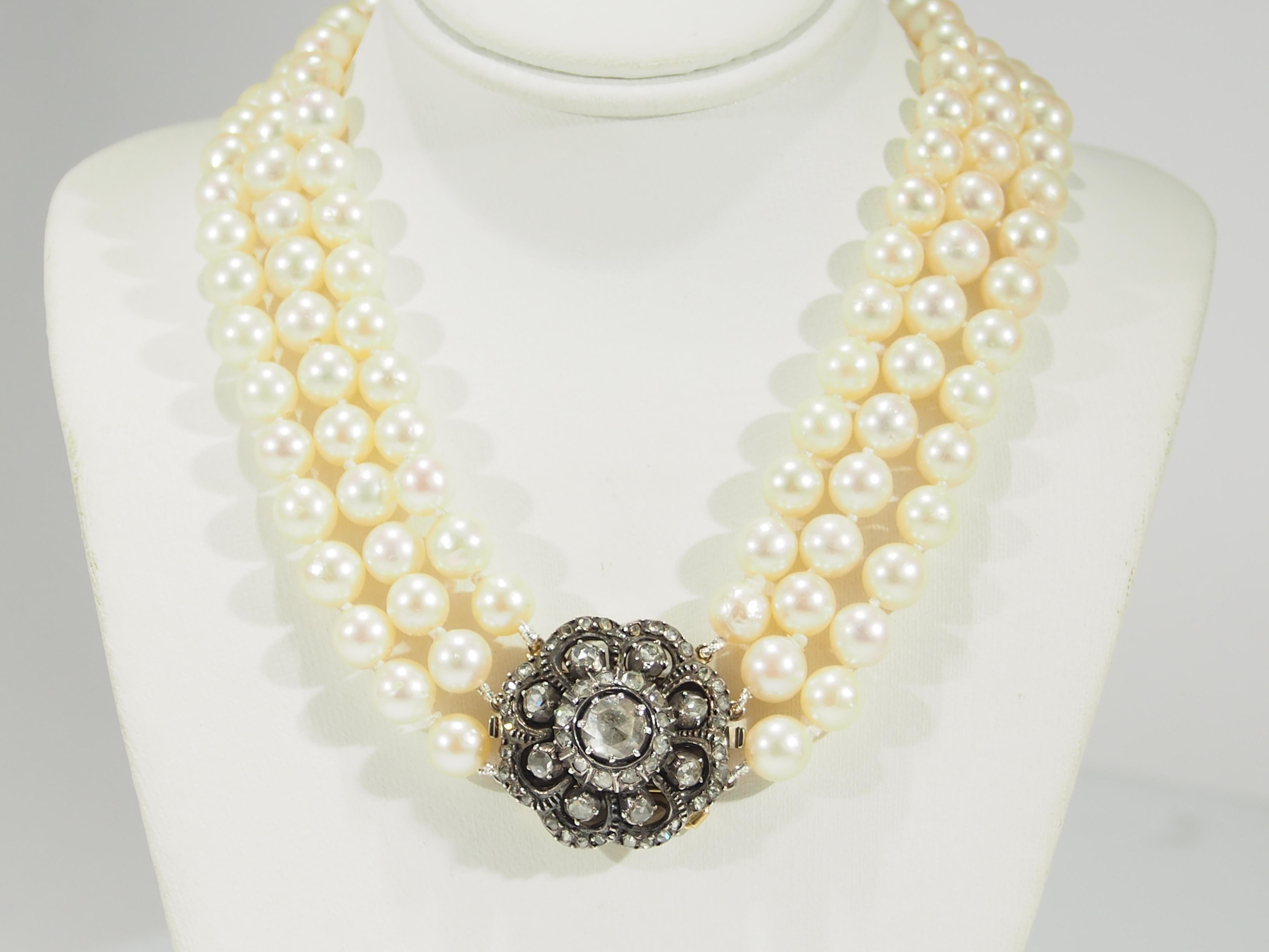 This is an heirloom quality Pearl Necklace fashioned with a 14K Yellow Gold Diamond Clasp. This exquisite Edwardian Necklace is designed in a triple row of lustrous 6.5mm Pearls with a 1 inch in diameter 14K Yellow Gold Clasp enhanced with a swirl