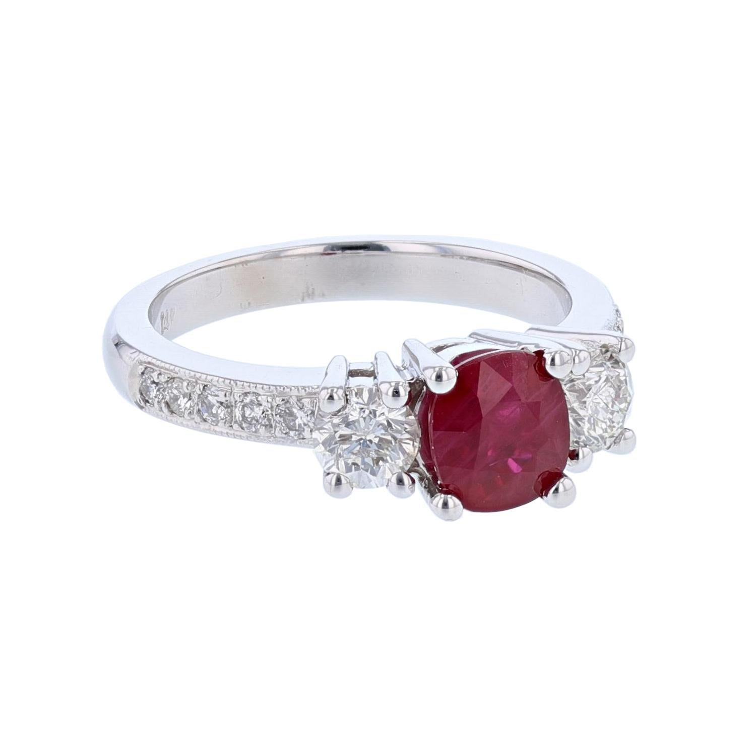 This ring is made in 14k white gold and features a Cushion cut Ruby weighing 1.36ct. The ring also features 2 prong set, round cut diamonds weighing 0.63cts  with a color grade (H) and clarity grade (SI2) and 10 round cut diamonds weighing 0.18cts