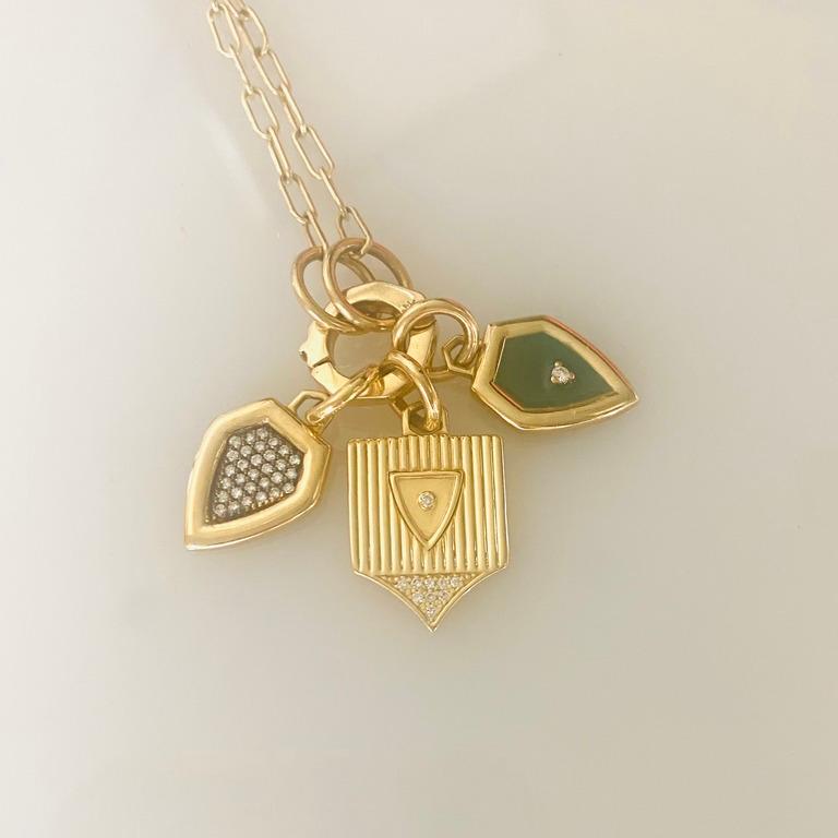 Our new, modern ribbed shield pendant shown here on an open chain with our charm holder.  This piece can be a foundation piece that can accommodate layered pendants.  This piece is a modern interpretation of a classical shield shape. 
14 karat gold,