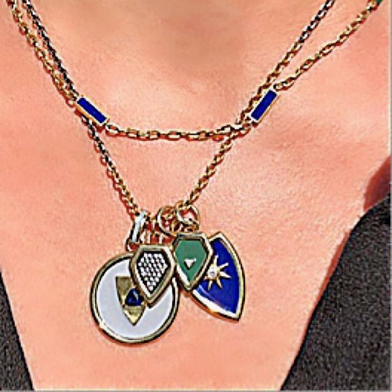 A modern version of a Victorian Fob.  This round pendant is rendered in pale grey enamel, with a gold shield design and a center blue sapphire trillion.  It hangs from a chunky oval jump ring with a stripe of grey enamel.  Stunning when worn alone,