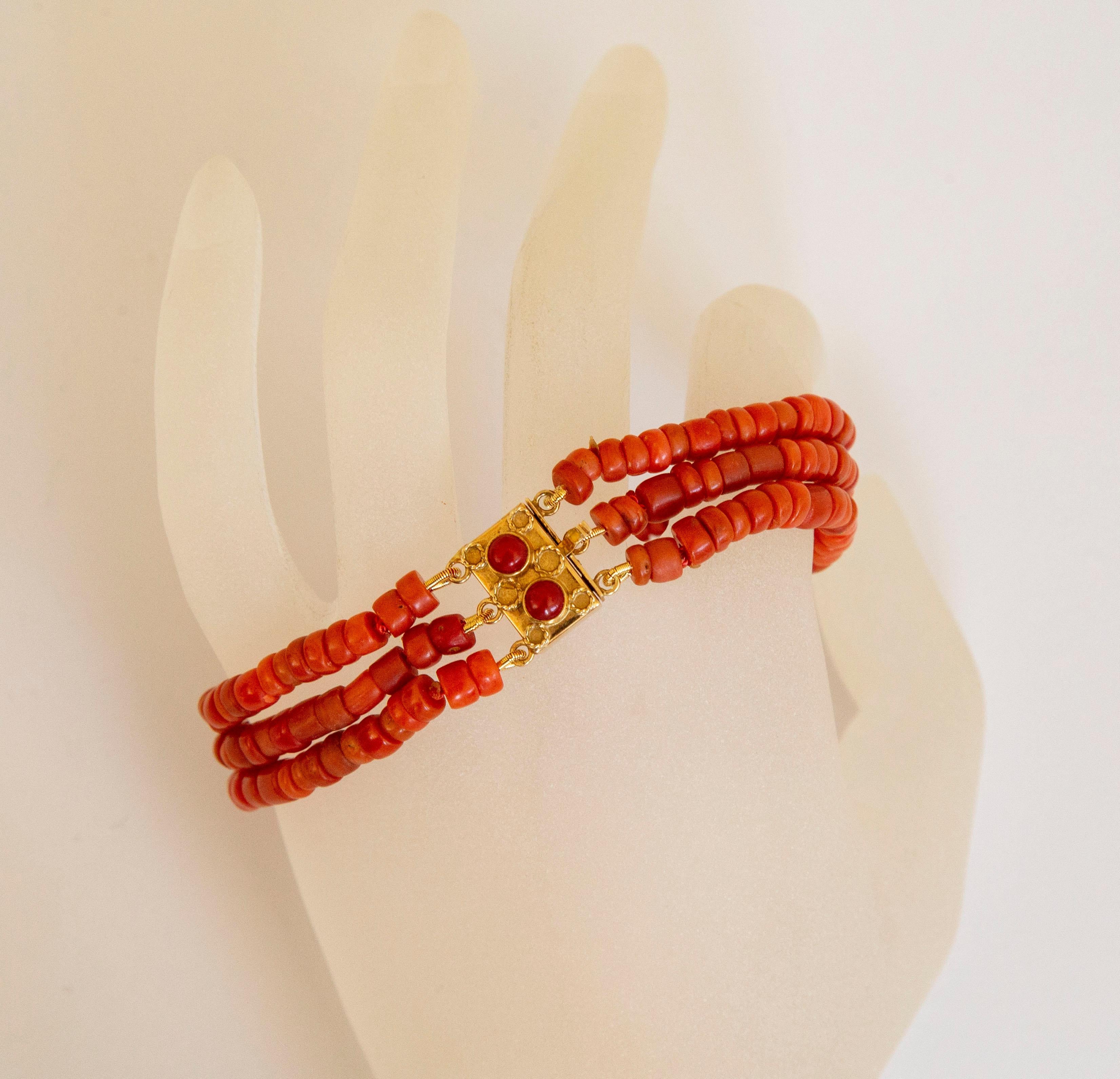 A vintage bracelet made of natural red coral beads with 14 karat golden clasp. The bracelet features three strands of barrel - shaped beads. The beads differ in the length from 3 mm till 6mm as well as in the color from pale to more saturated
