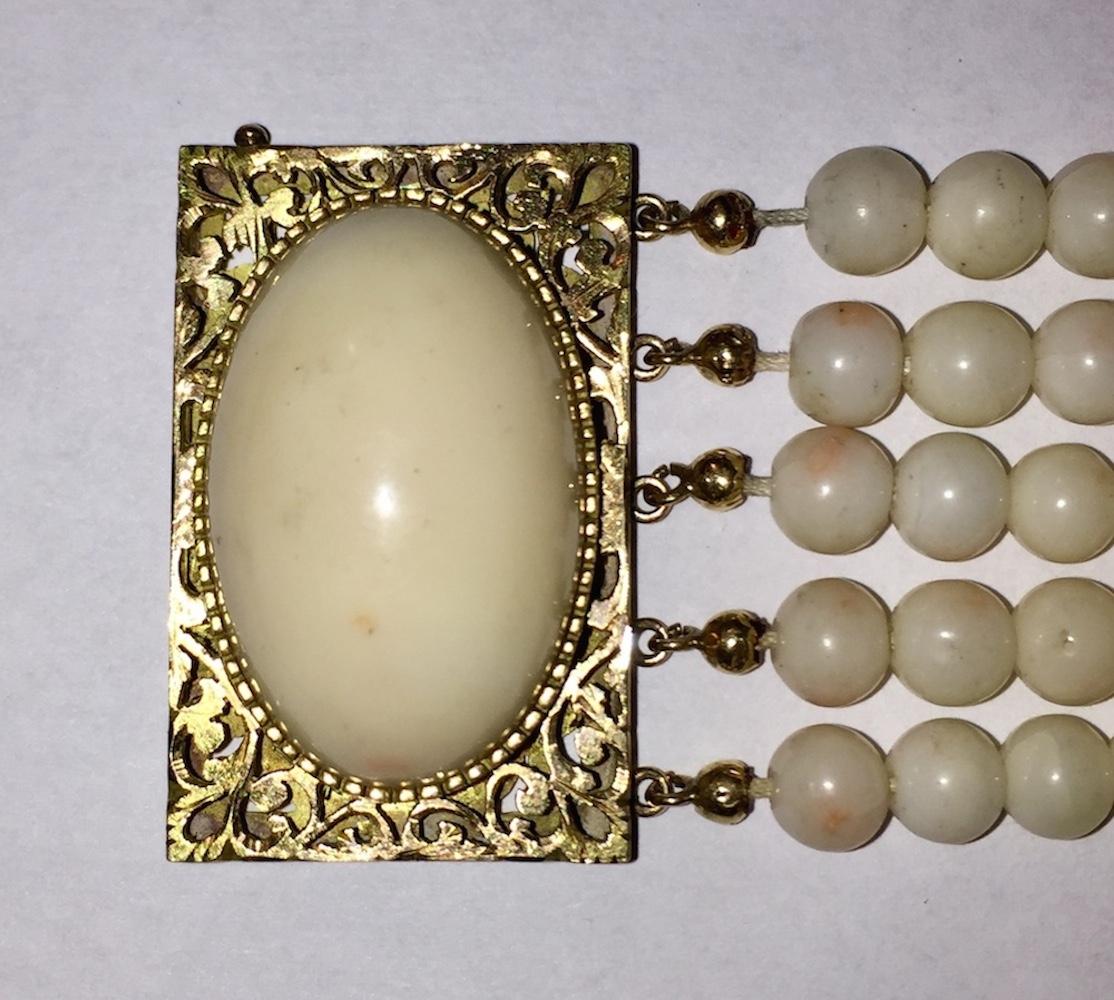 14 karat yellow gold filigree hollow box clasp with large angel skin coral cabochon and 5 rows of angel skin coral beads. Cabochon measures 28 mms by 18 mms. Bracelet is 1.5” wide and 8” long. Marked, 14 kt. Back of box clasp has hand etched design.