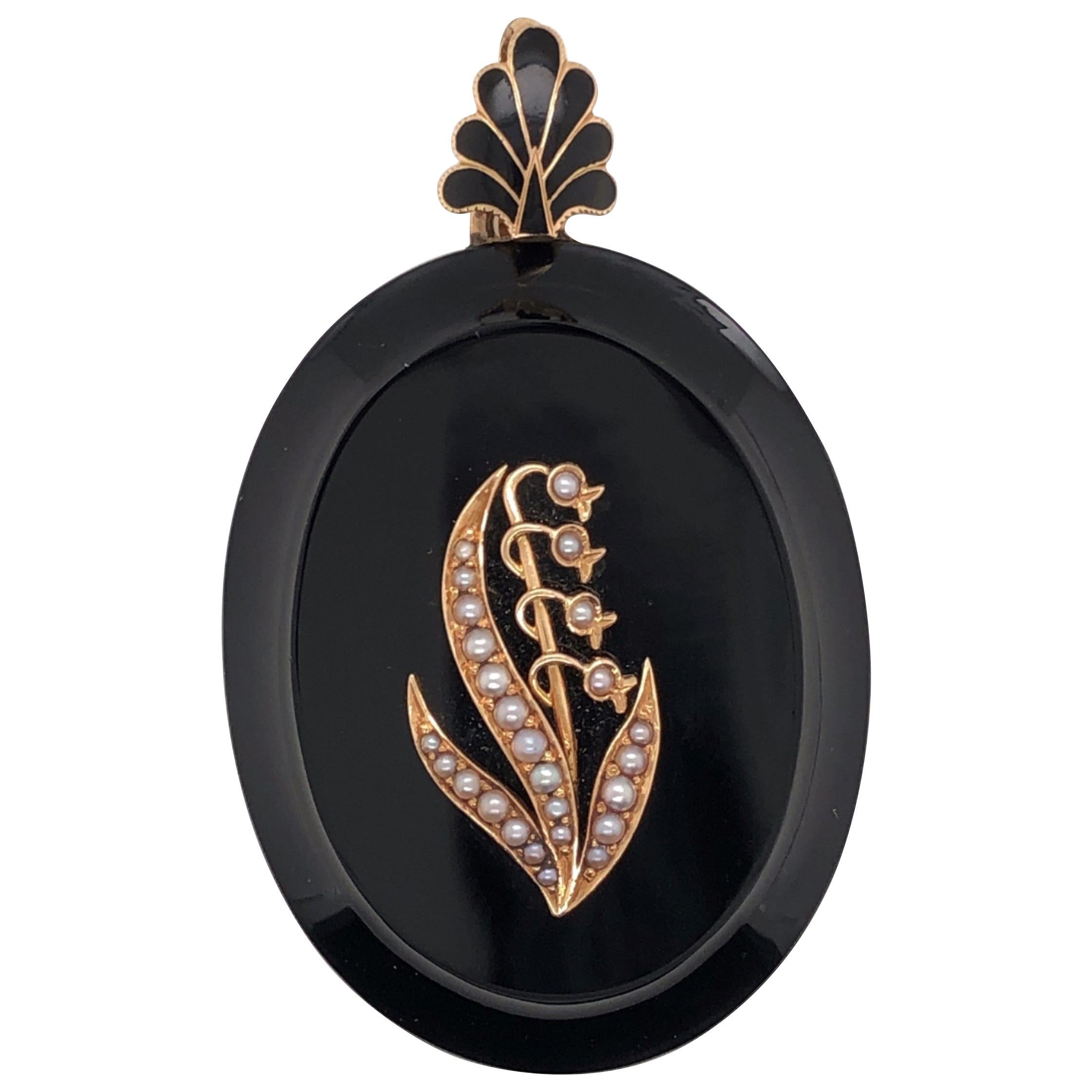 This is a gorgeous Victorian locket, circa 1880-1890, in fabulous condition! The body of the locket is made of black onyx and the bail is made of 14kt yellow gold with black enamel. The front face of the locket displays a Lily of the Valley made of