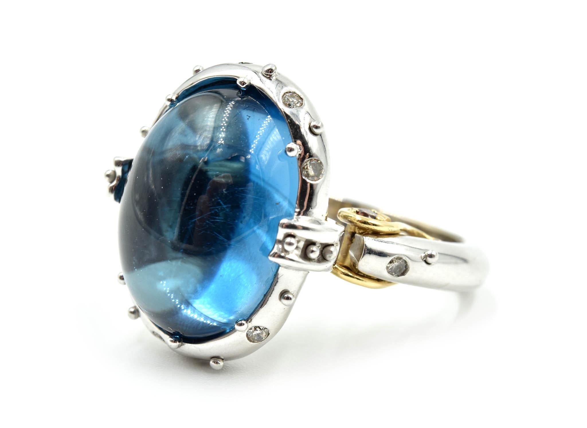 Add personality to your jewelry collection with this cabochon blue topaz cocktail ring featuring cognac and white diamond accents! The 22.60ct blue topaz center stone is set on the top of the unique wrapping style mounting, bezel set with diamonds!