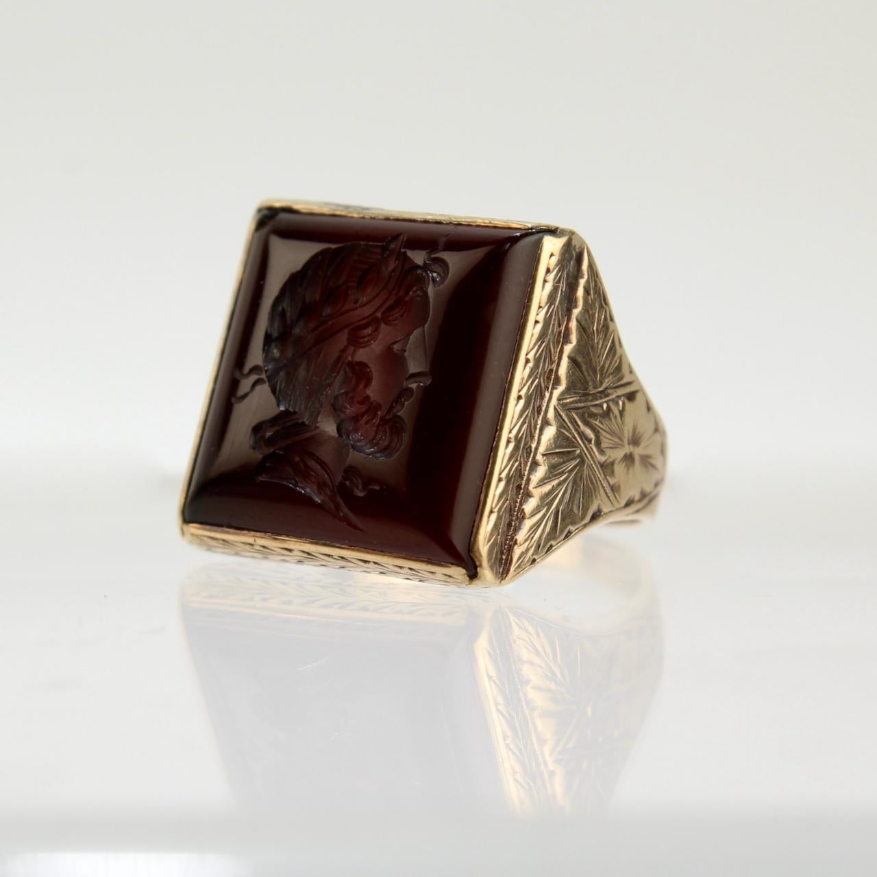 Offered here for your consideration is a 14K gold signet ring.

With a carved cameo in the center of a square carnelian cabochon that is bezel set in 14 karat gold. 

The setting has a floral engraved bridge and shank.

Date:
Late 19th or Early 20th