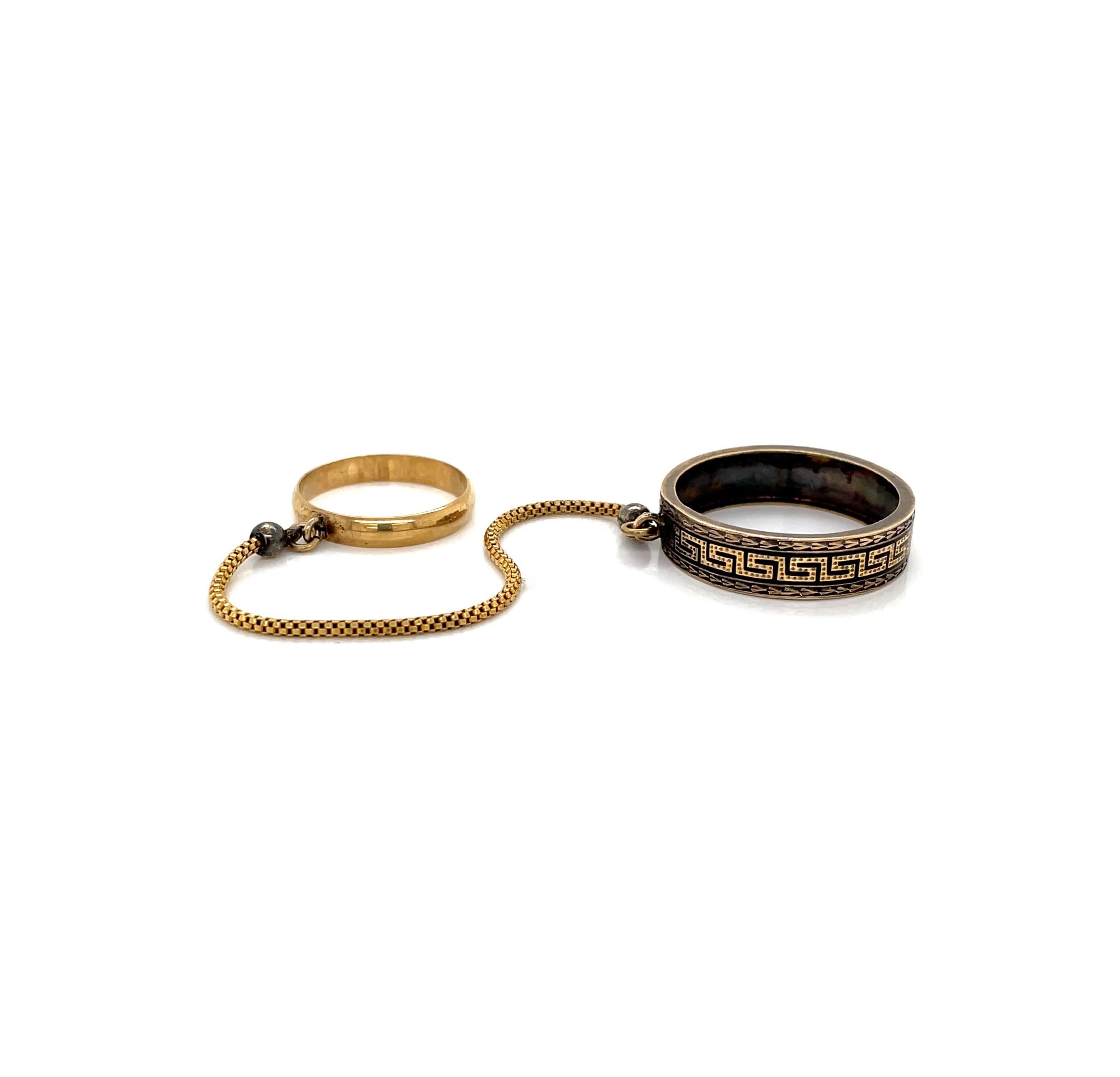 For an exotic look, a decorative 5.8mm band of gold with a engraved Greek design accented by black enamel anchors this ring pair from the middle finger, in size 10-1/4. As if handcuffed, a three inch 1.40mm round Venetian 14 karat gold chain