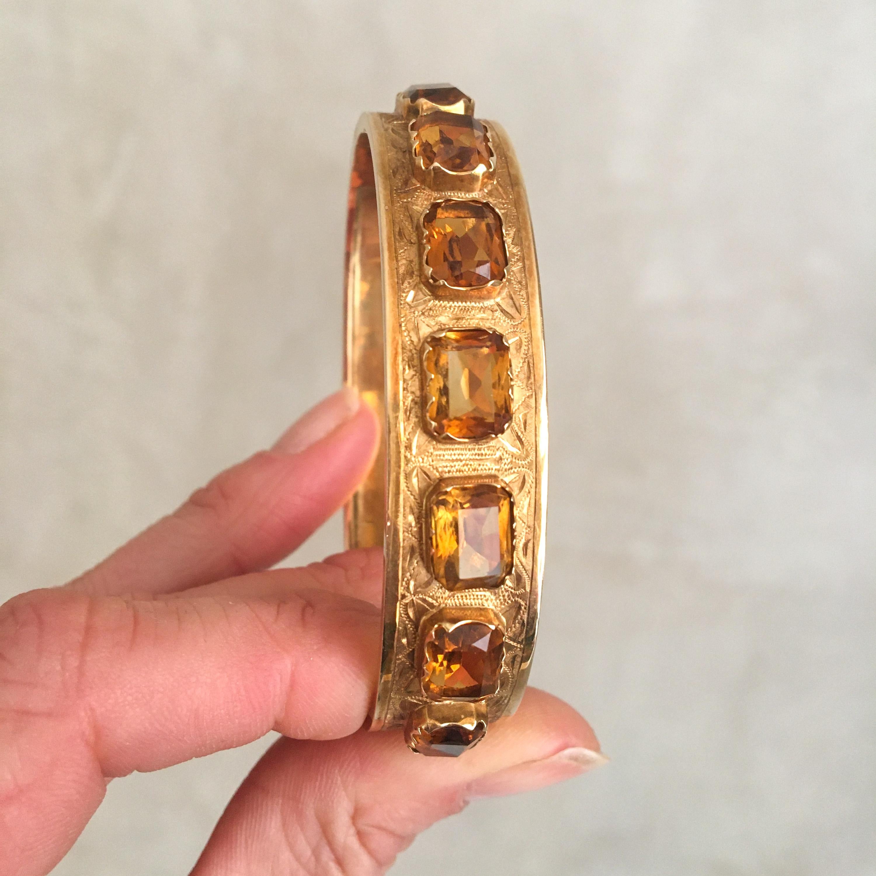 A beautiful early 20th century hinged bangle bracelet set with seven citrine gemstones. The citrine stones have a lovely honey colored hue and sparkle with a radiant beauty. Each rectangular citrine is separately set in a 14 karat yellow gold frame