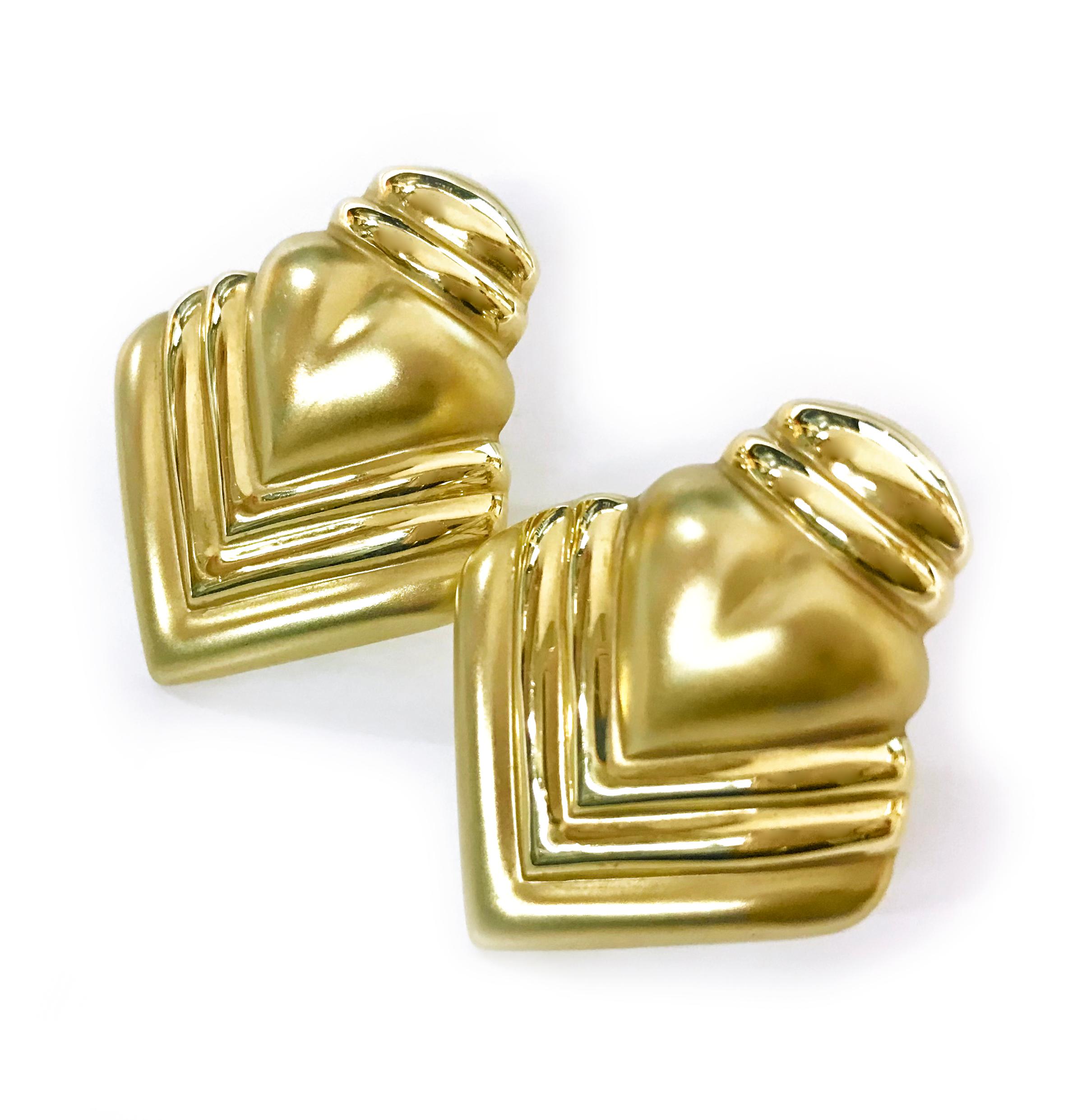 14 Karat Gold Ridged Heart Earrings. These lightweight clip-on earrings make a statement with their bold heart design. The earrings have an Art Deco style design and both satin and smooth shiny finish. The earrings have an Omega clip and a total