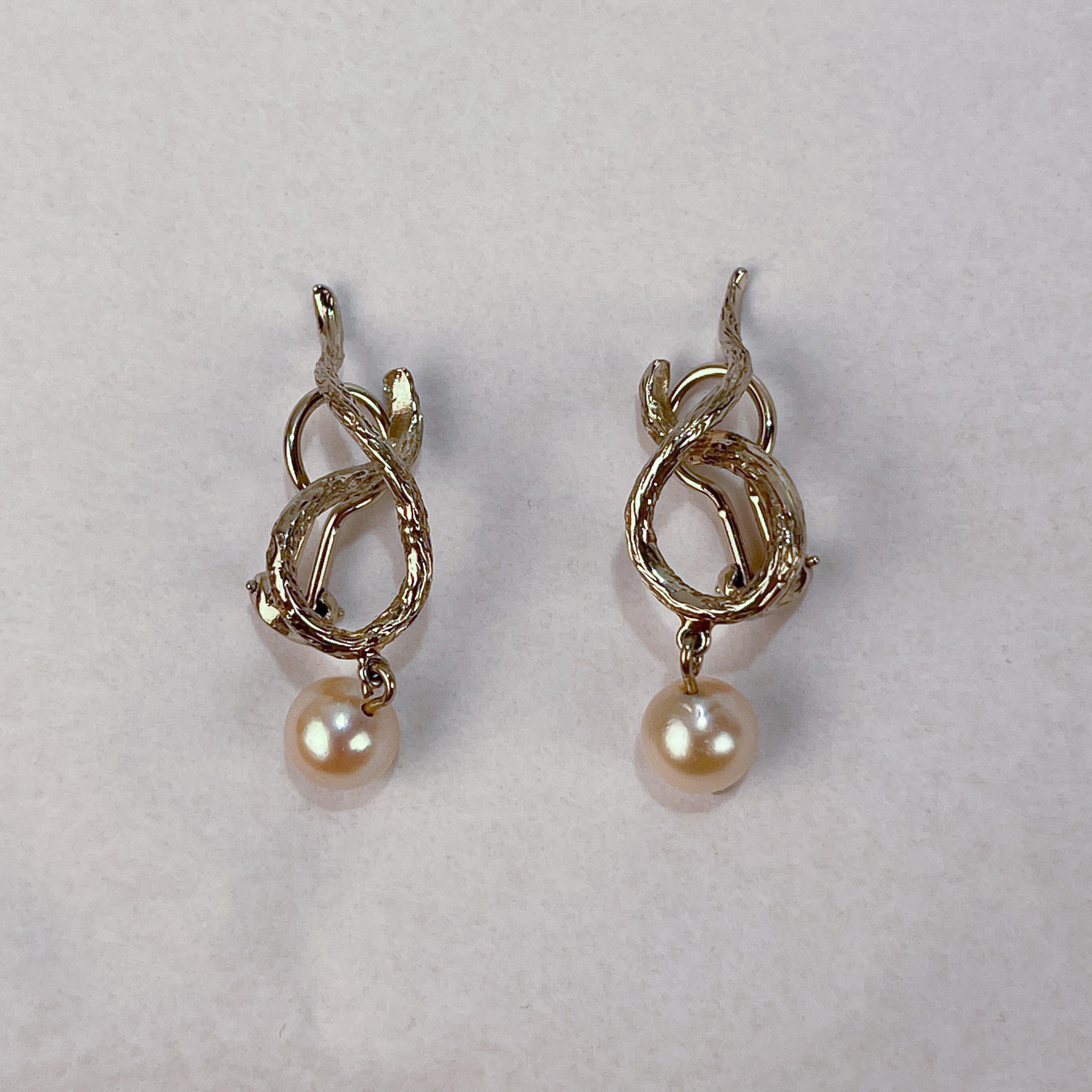 A very fine pair of gold and pearl clip-on earrings.

In textured 14k gold with a snake-like design and a dangling pearl at the bottom of the earring. 

Simply a great pair of eye-catching earrings!

Date:
20th Century

Overall Condition:
They are