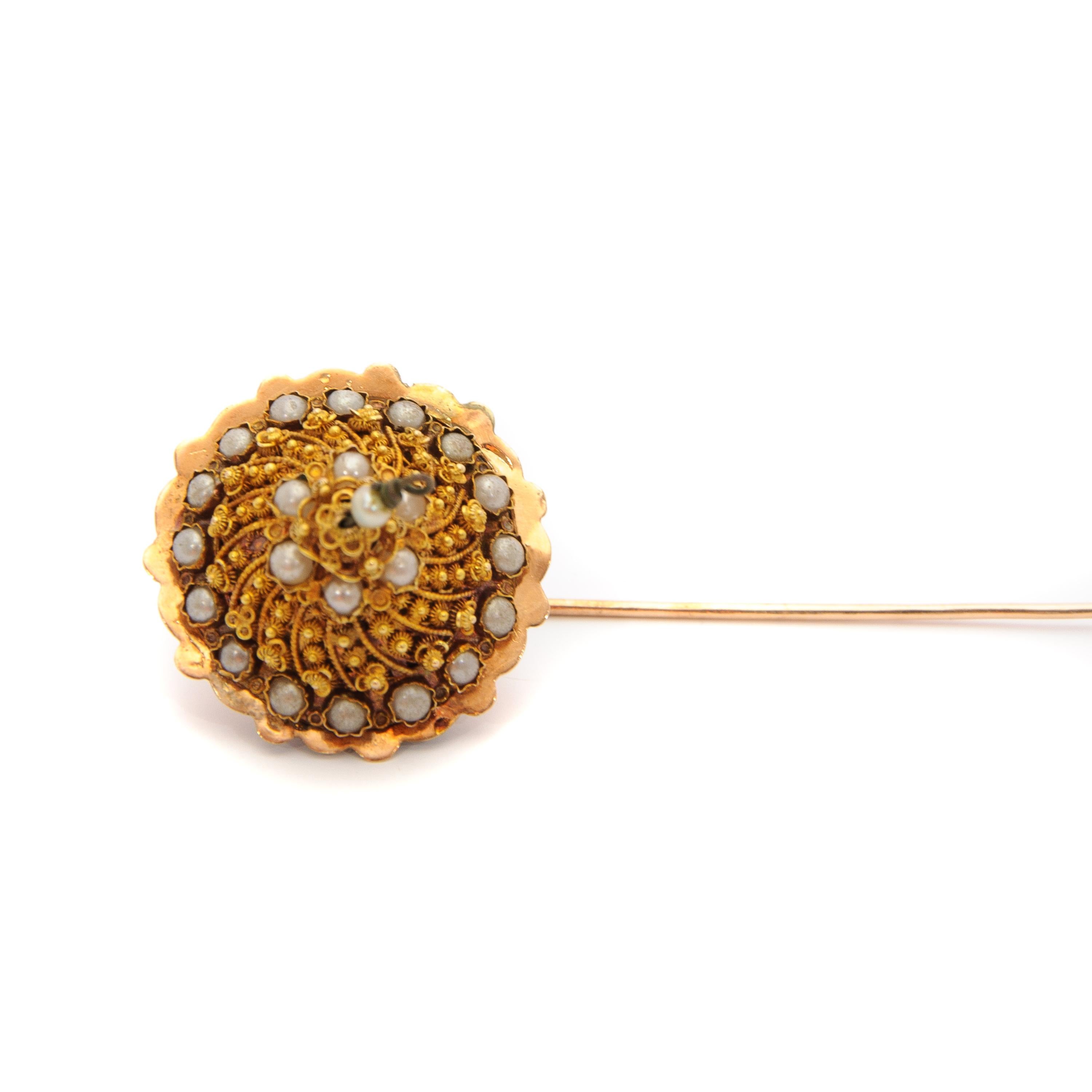 This antique 19th century stick pin is made of 14 karat gold and seed pearls. This beautiful stick pin is made of fine cannetille work, which is applied on top of the pin. The cannetille work is skillfully handcrafted and gives the impression of