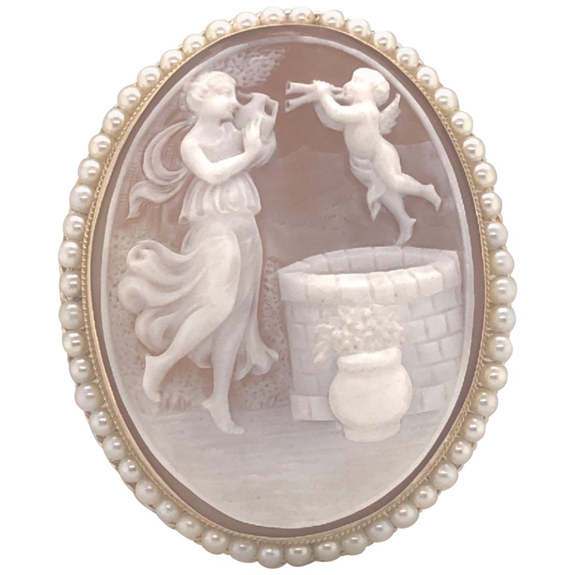 14kt yellow gold cameo with pearl frame. The carving of the natural shell cameo is a modern interpretation of the story of Rebecca at the Well- a Biblical story of Abraham finding Isaac a wife. The cameo is hand carved from natural helmet shell. It