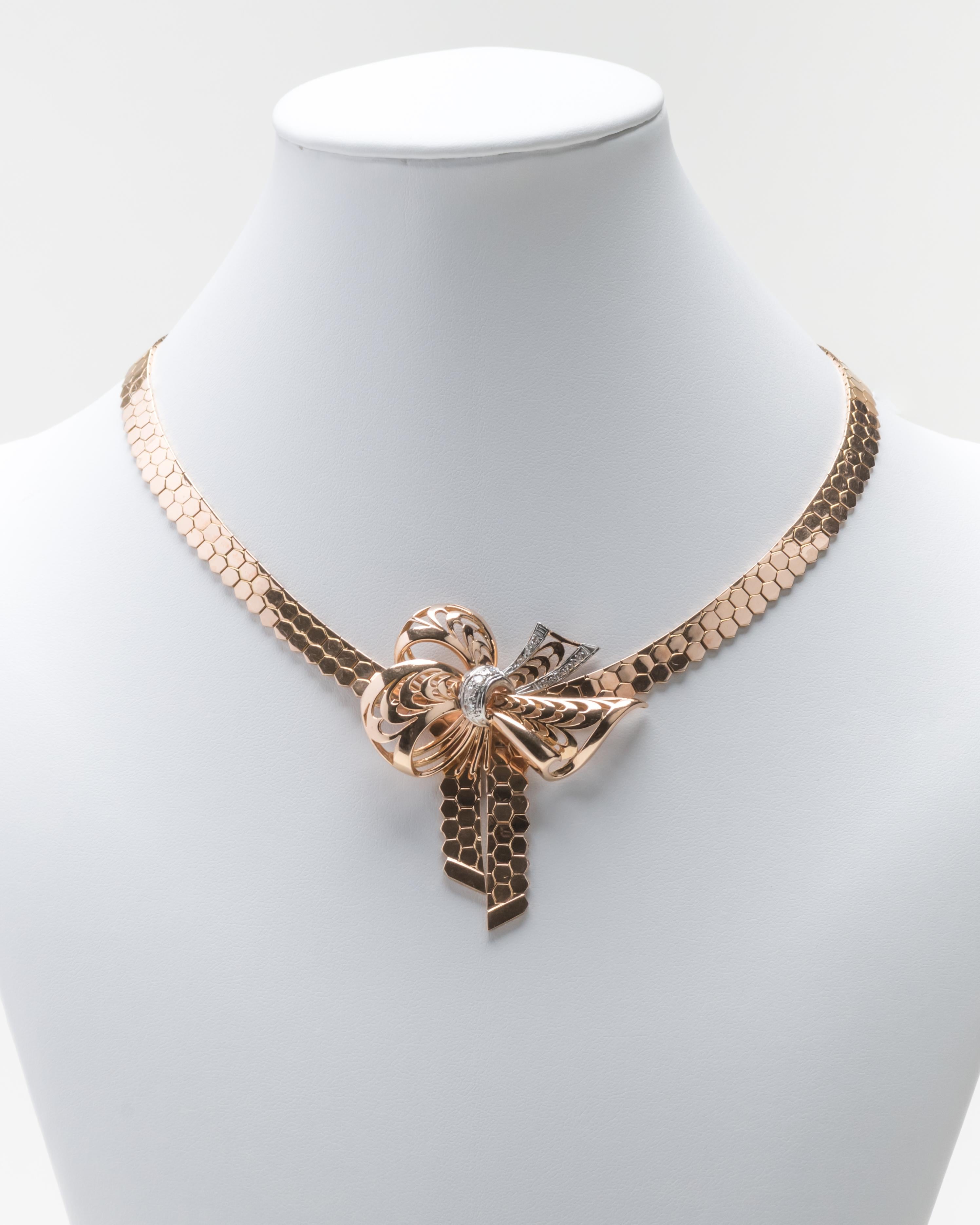 Finely detailed retro 14 karat rose gold necklace with a geometric chain connecting to a central bow with diamonds inset in white gold. The necklace has superior design and craftsmanship.

Size: L: 16.75