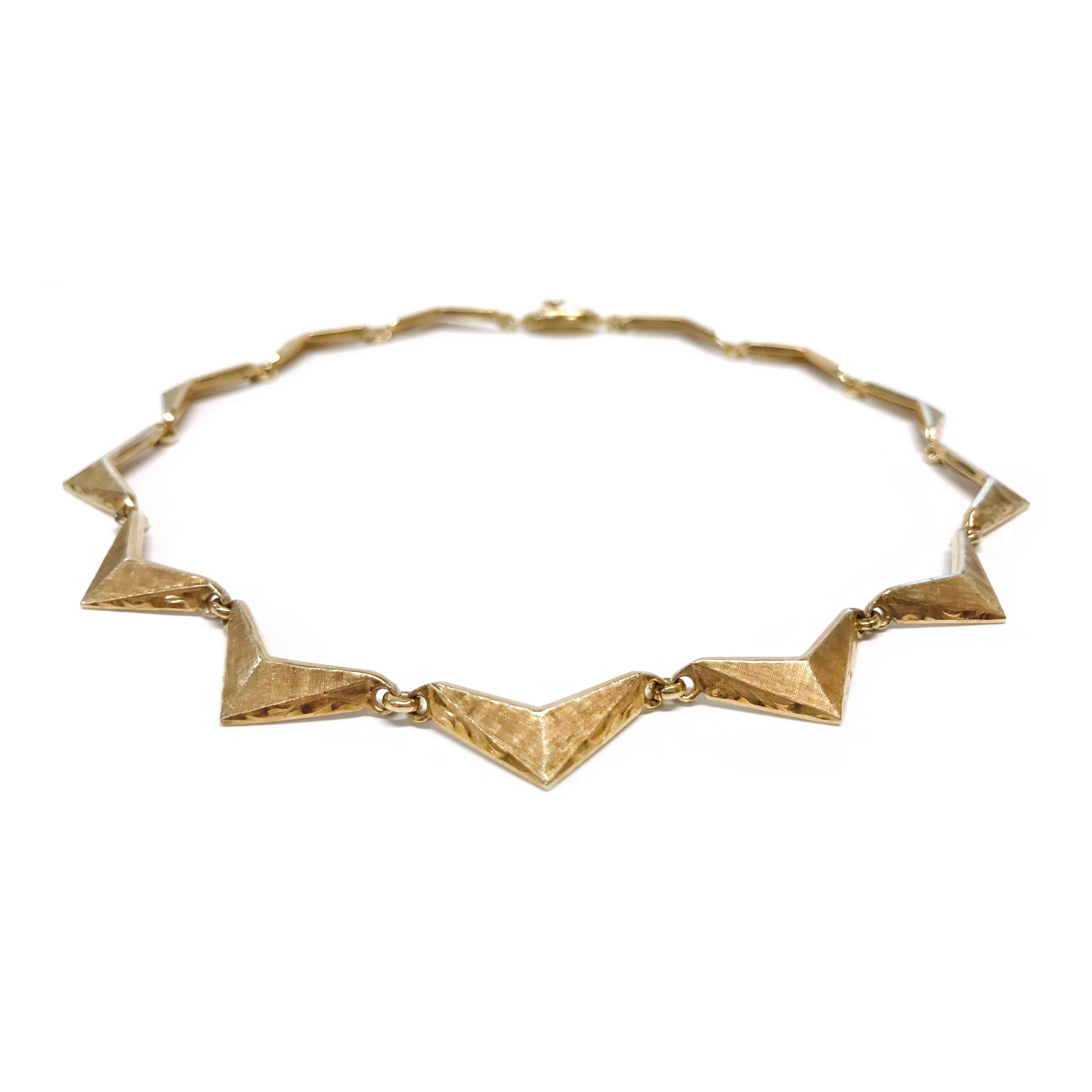 14 Karat Gold Triangle/Chevron Link Necklace. The necklace consists of thirteen gold triangles linked together. The triangles have a Florentine finish on the front and smooth shiny finish on the sides and back. Stamped on the inside of the clasp is